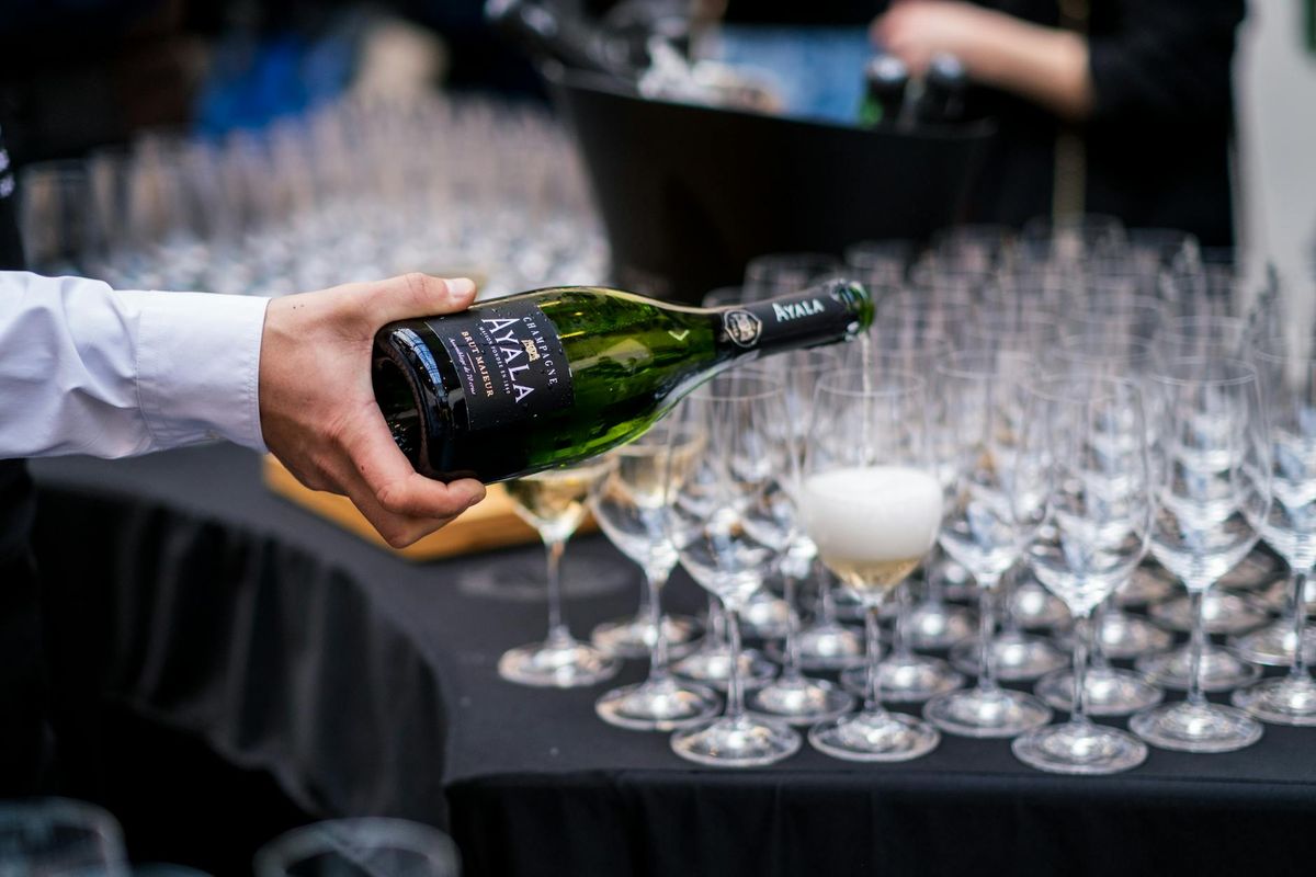 A waiter pours champagne into glasses at a sophisticated Parisian event.