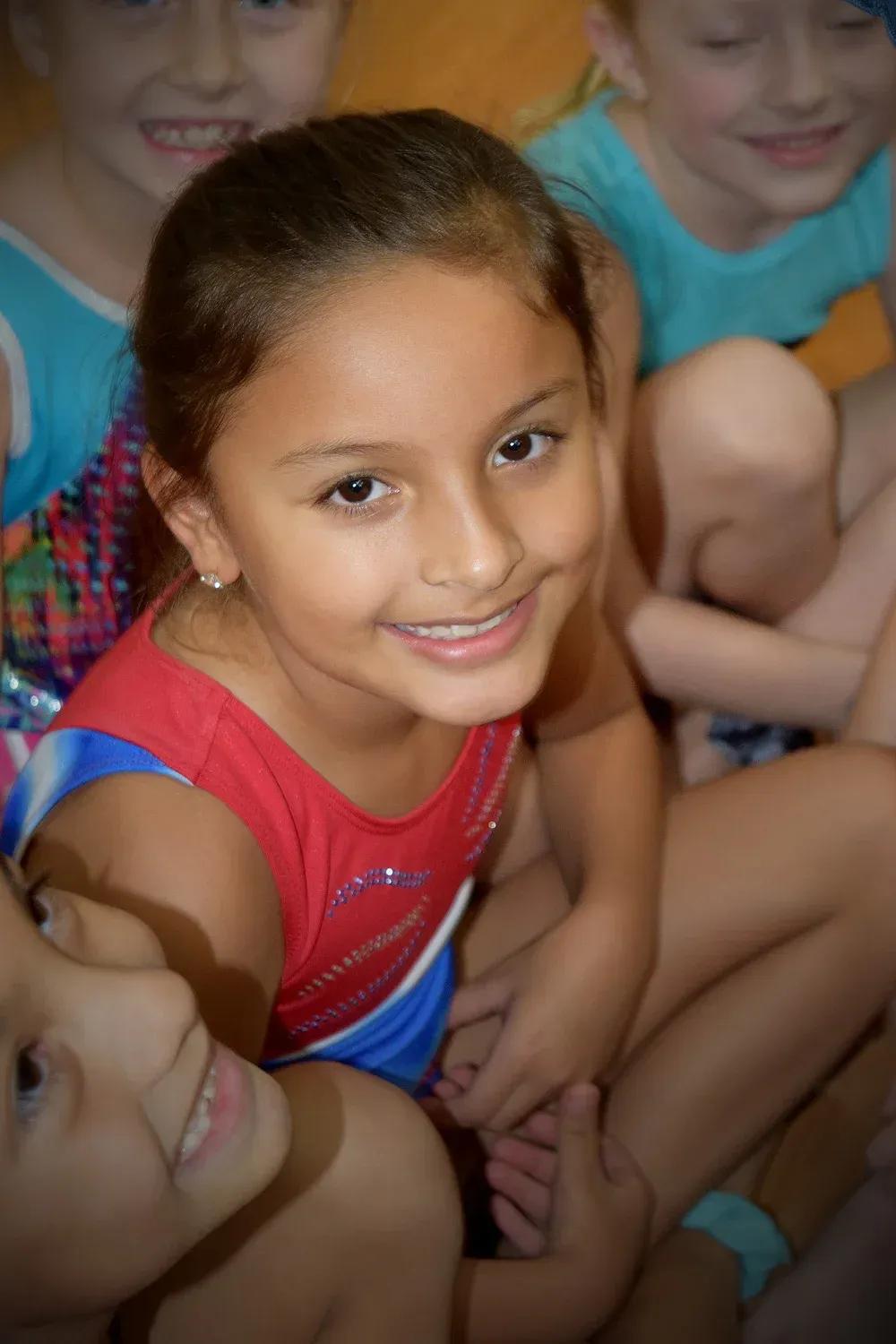 Young gymnast in a red leotard performing in a Novas beginner class