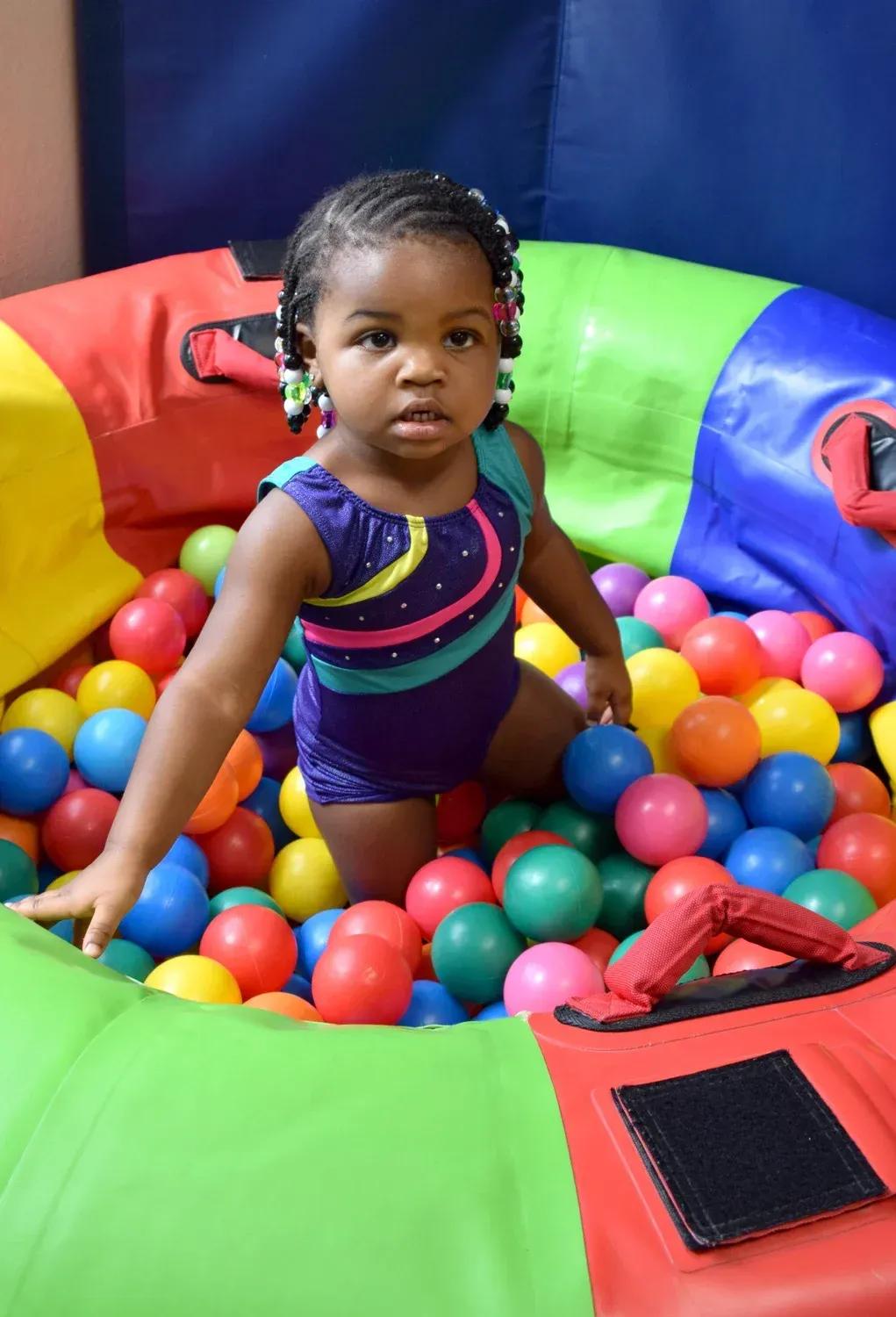 Preschooler practicing a skill on the balance beam in a Tiny Tot class