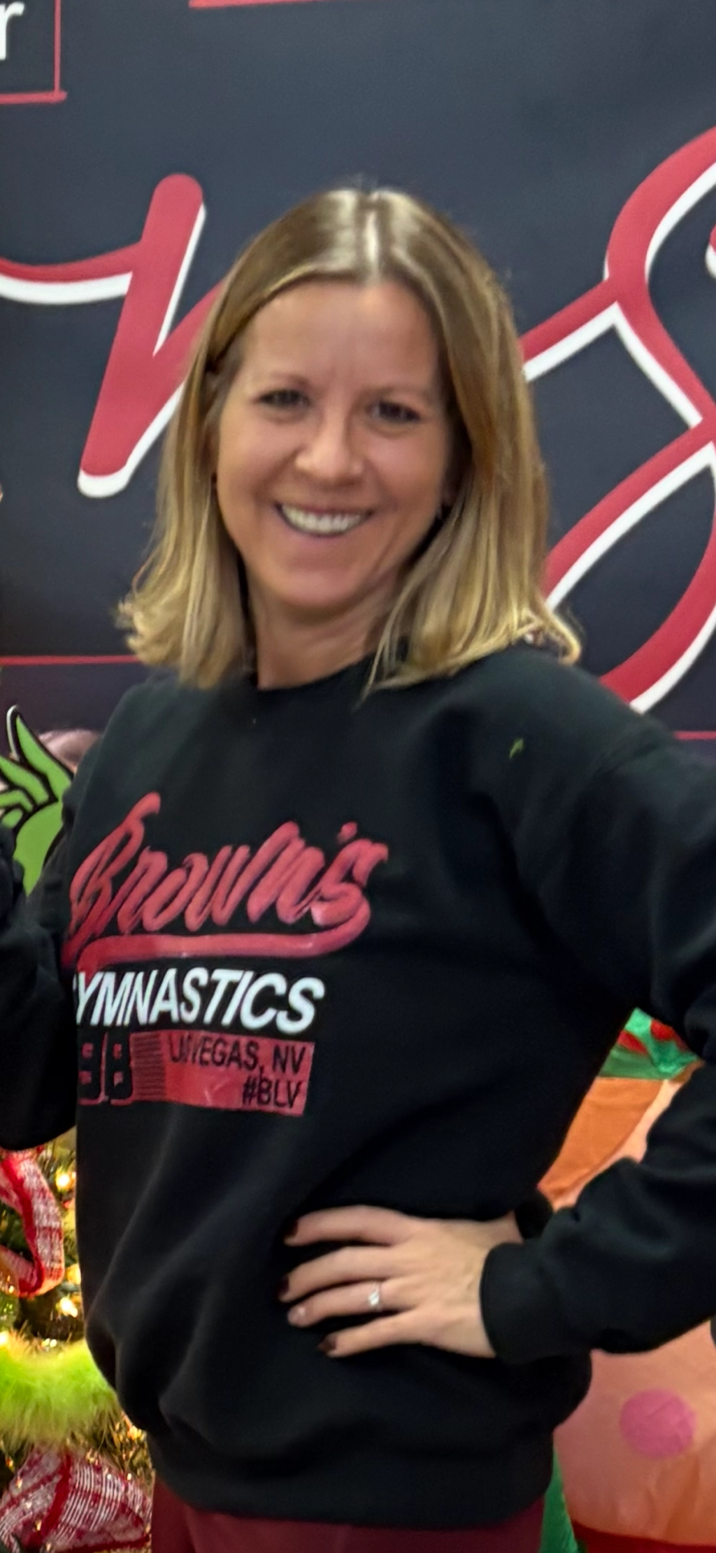 Team Coach Elena Tiron smiling in front of the Brown’s Gymnastics backdrop