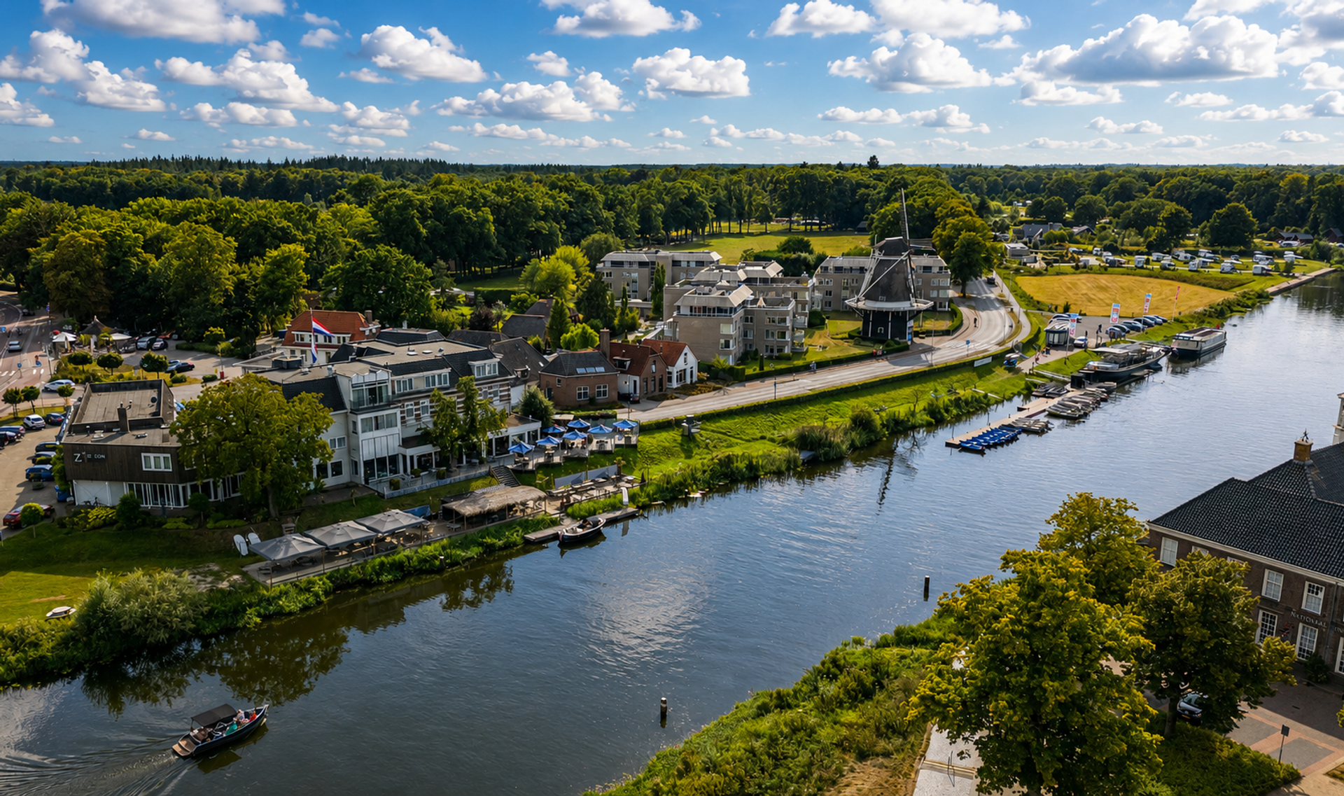 Luchtfoto van Hotel de Zon aan de Vecht in Ommen met terras, molen en boten op het water