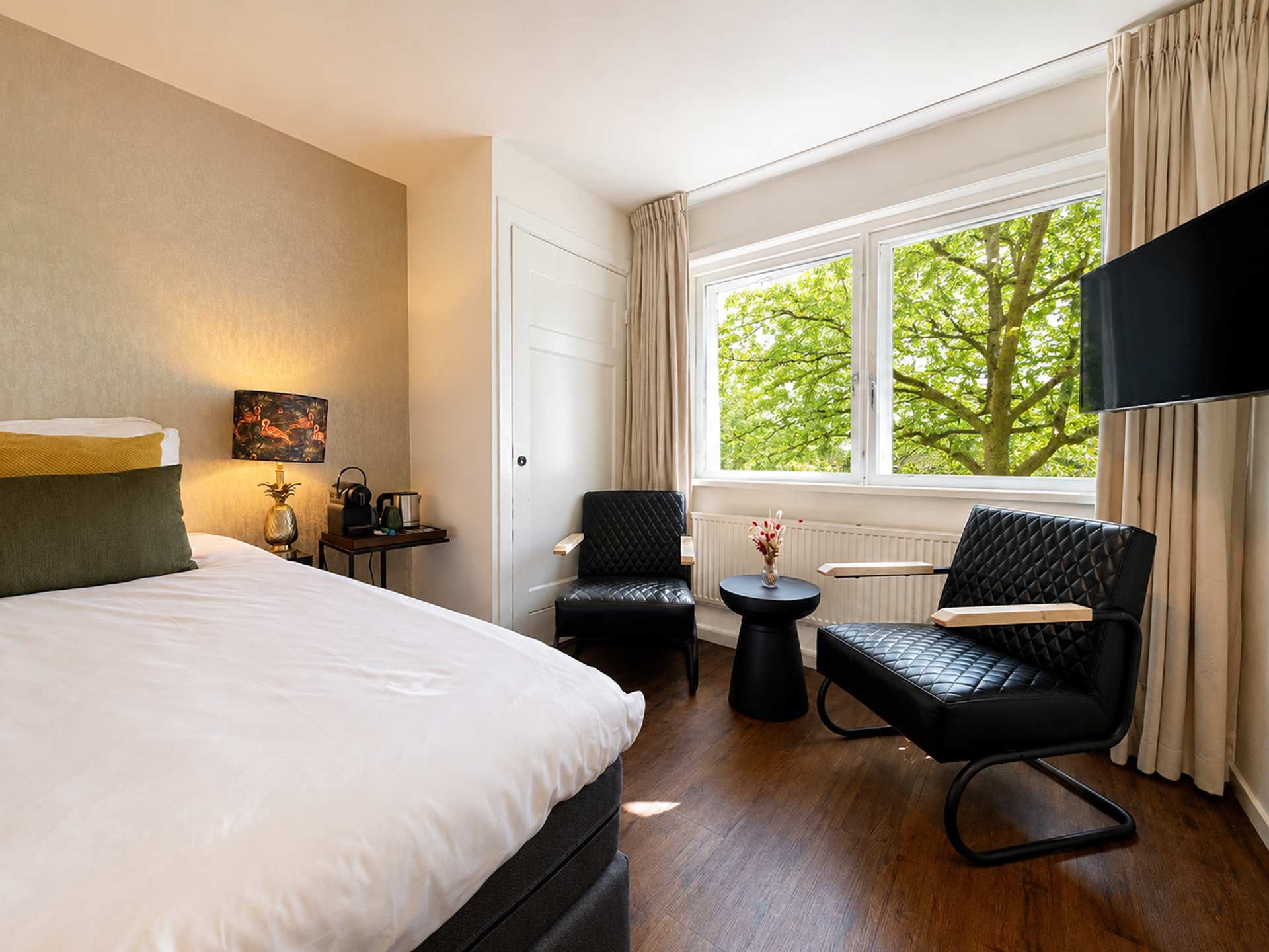 Hotelkamer met tweepersoonsbed, zithoek en uitzicht op het groen bij Hotel Paping in Ommen, Vechtdal