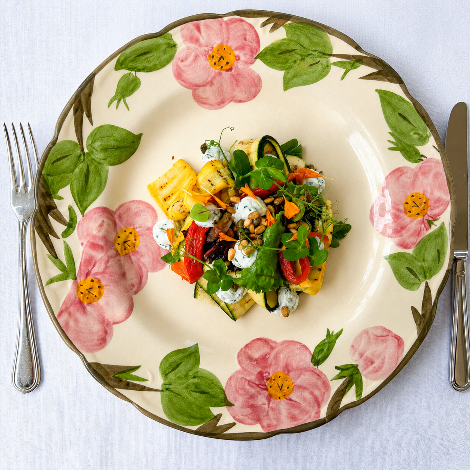 Gegrilde groenten met ricotta, pijnboompitten en microgreens op een handbeschilderd bloemenbord bij restaurant Luigi's in Winselerhof