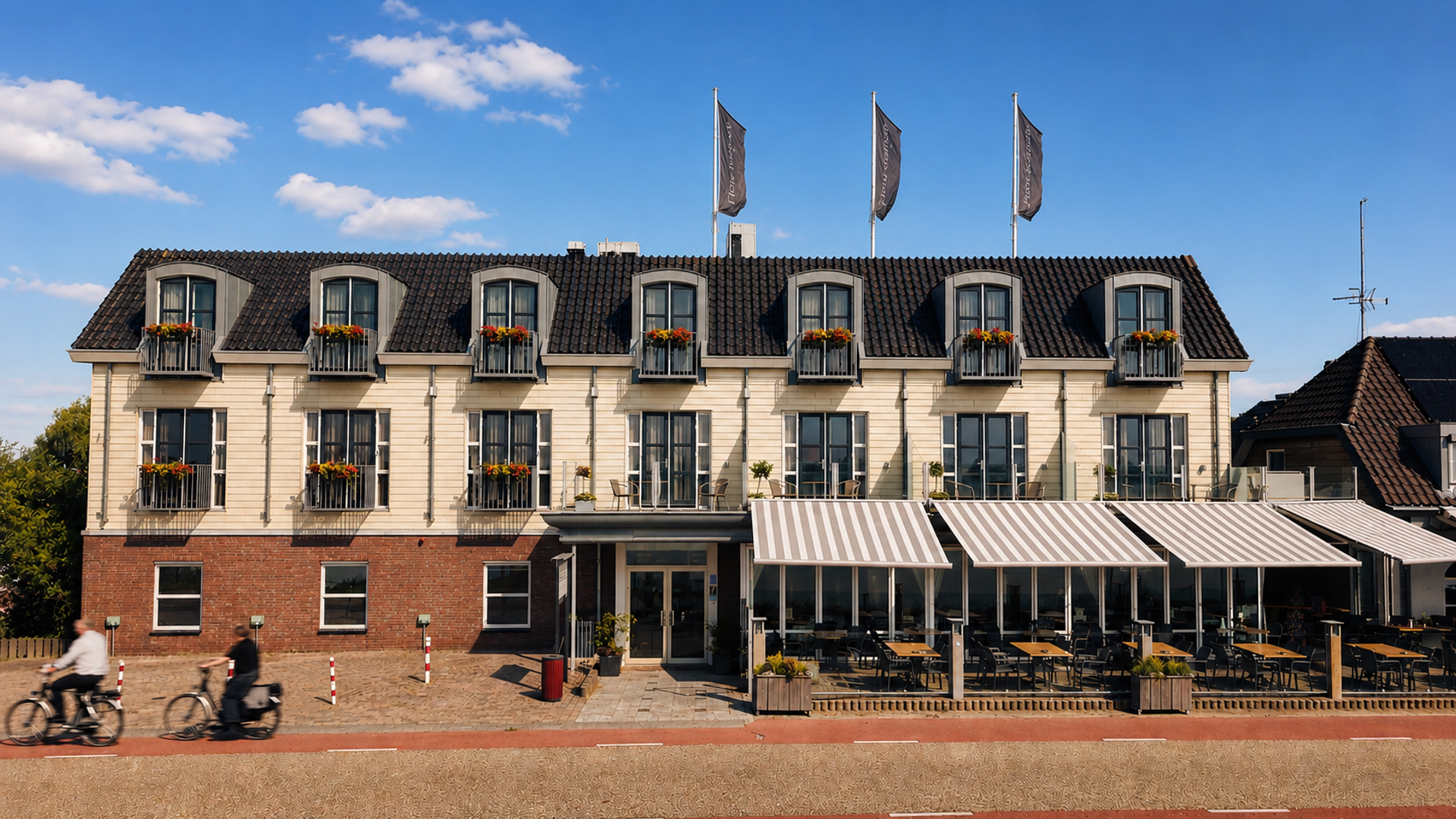 Voorgevel van Hotel Hoogeerd in Niftrik met fietsers op het terras