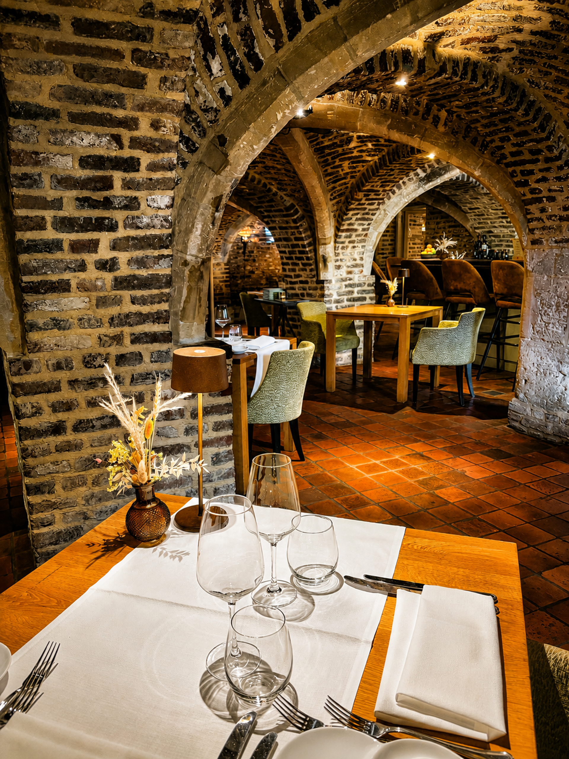 Gedekte tafels in de historische gewelfde zaal van restaurant Luigi's in Winselerhof met terracotta vloer en tafellampjes