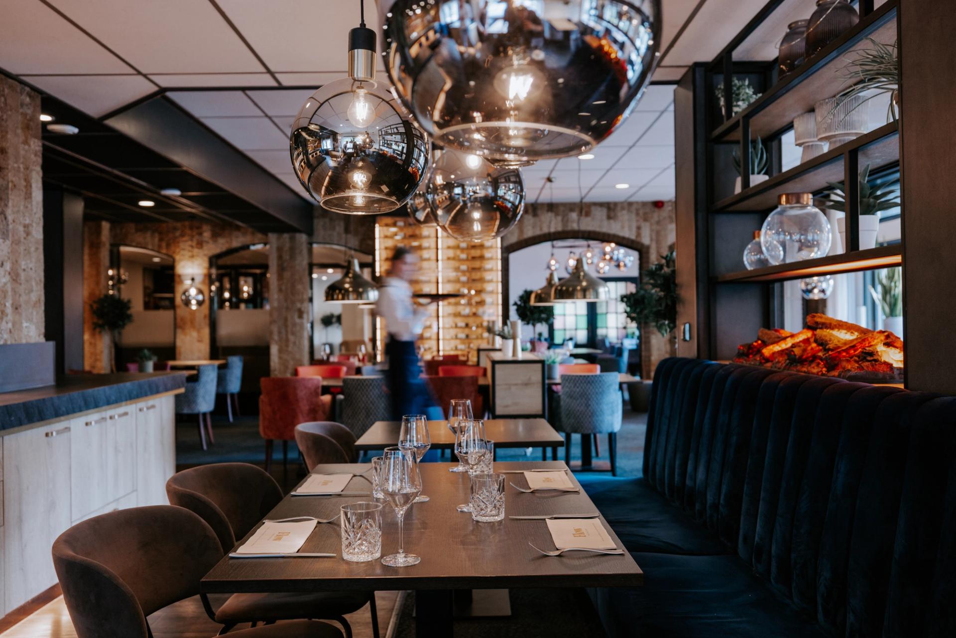 Stijlvol restaurant van Hotel de Oringer Marke in Odoorn met sfeervolle verlichting, open haard en gedekte tafels