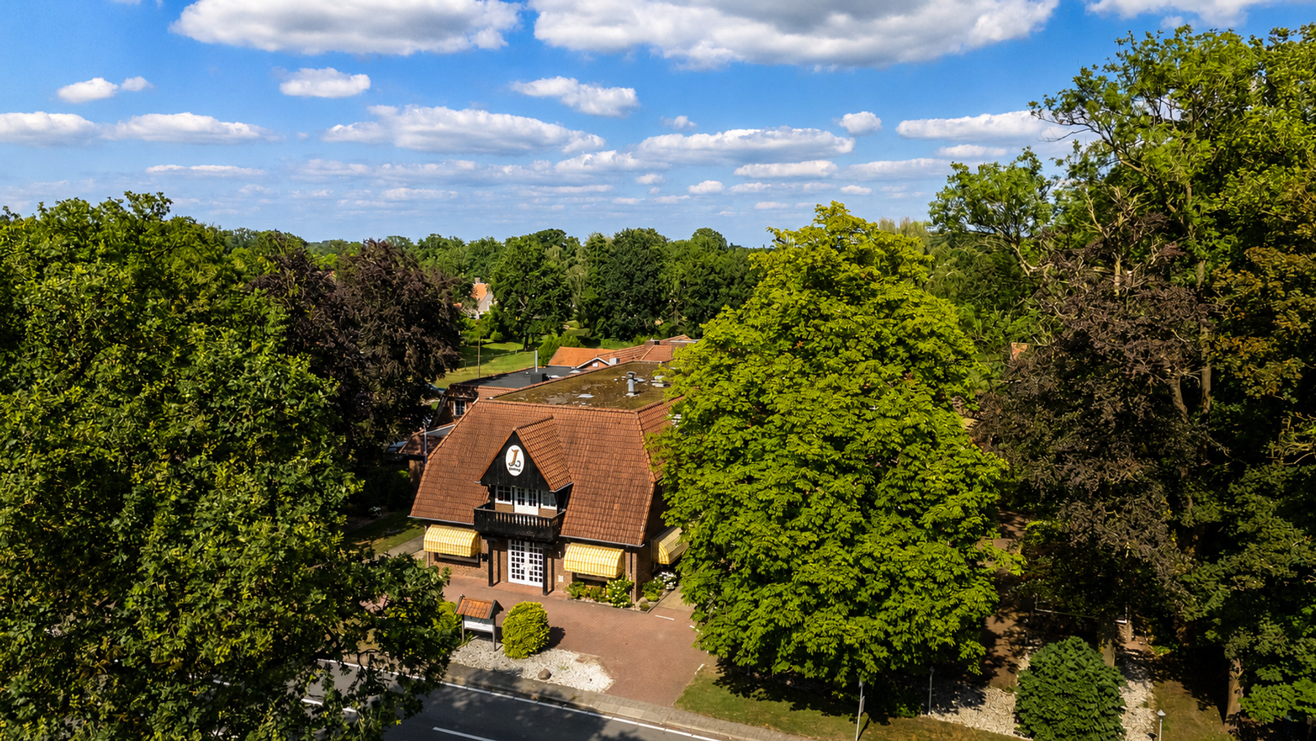 Luftaufnahme des Hotel de Landmarke in Ootmarsum, eingebettet zwischen Bäumen mit hügeliger Twentse Landschaft im Hintergrund