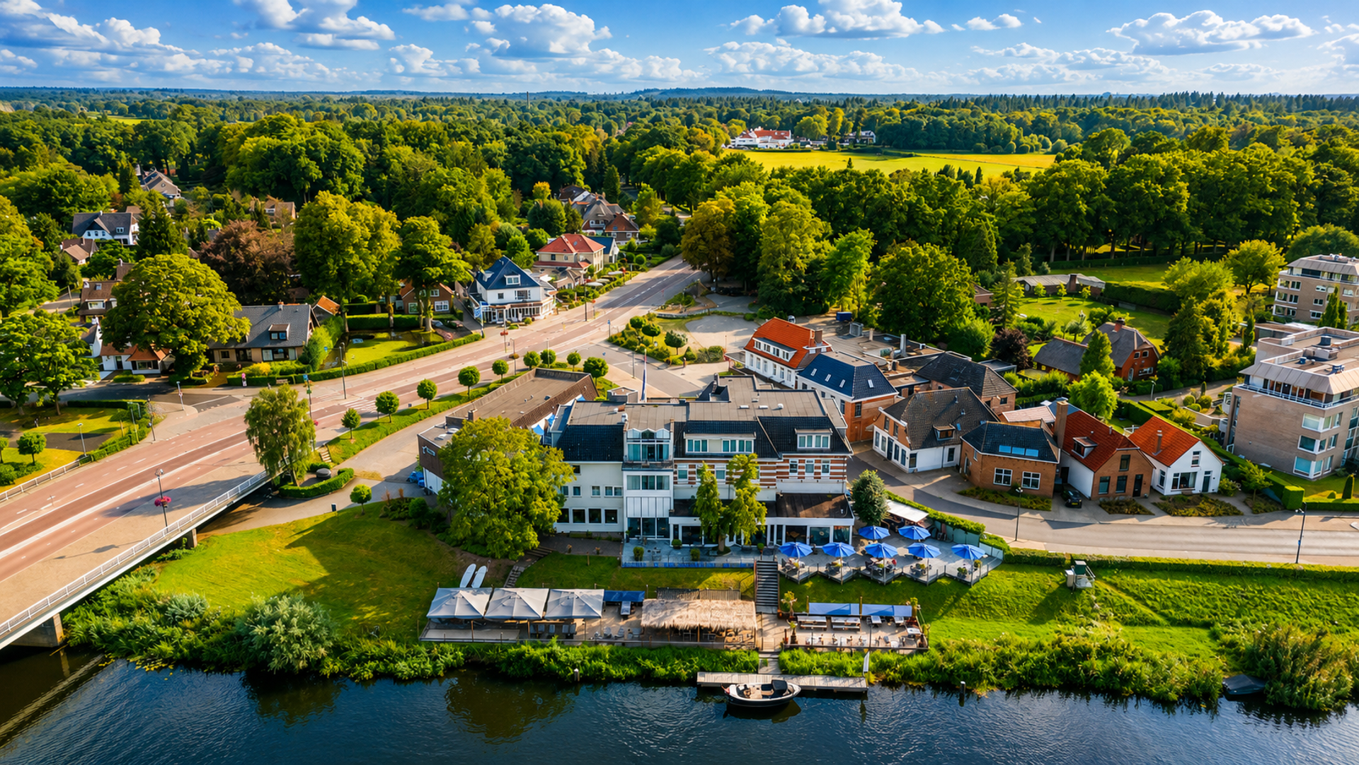 Luchtfoto van Hotel de Zon aan de Vecht in Ommen met terras, strandbar en groene omgeving