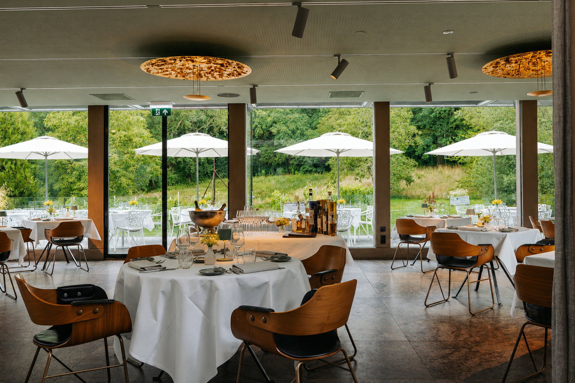 Lichte eetzaal van restaurant Pirandello in Winselerhof met witte tafels, houten stoelen en panoramisch uitzicht op de tuin