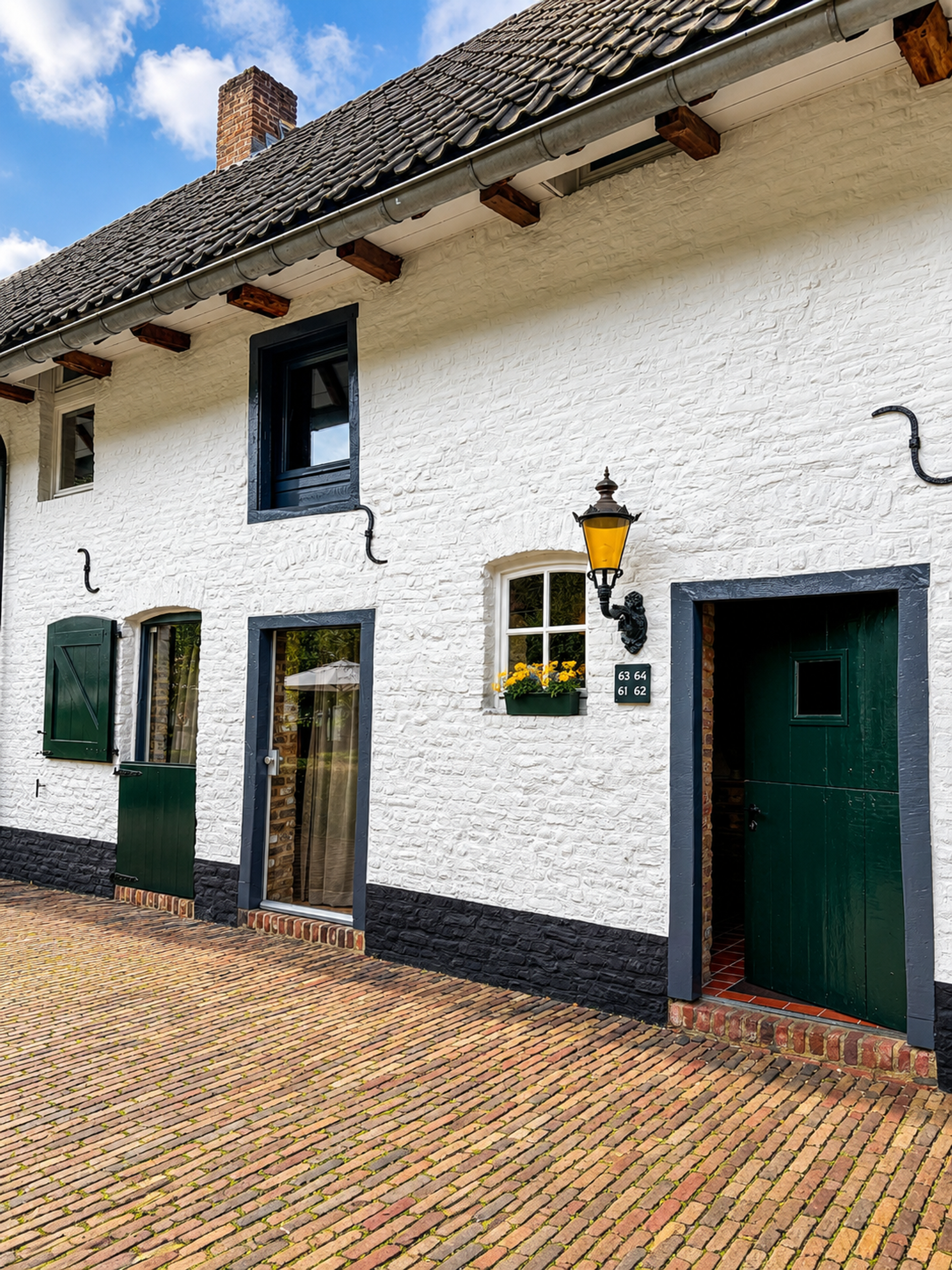 Authentieke gevel van Landgoed Winselerhof in Zuid-Limburg met witgekalkte muur, groene luiken en gele lantaarn