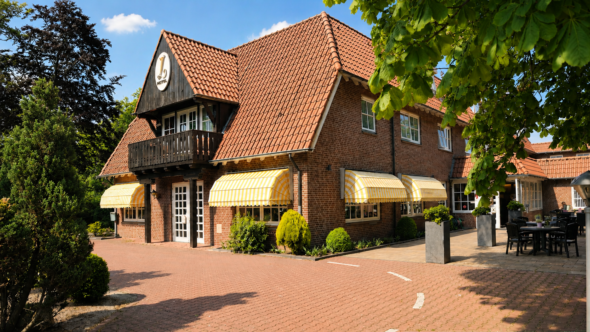 Karakteristiek pand van Hotel de Landmarke in Ootmarsum met bakstenen gevel, gele luifels en terras