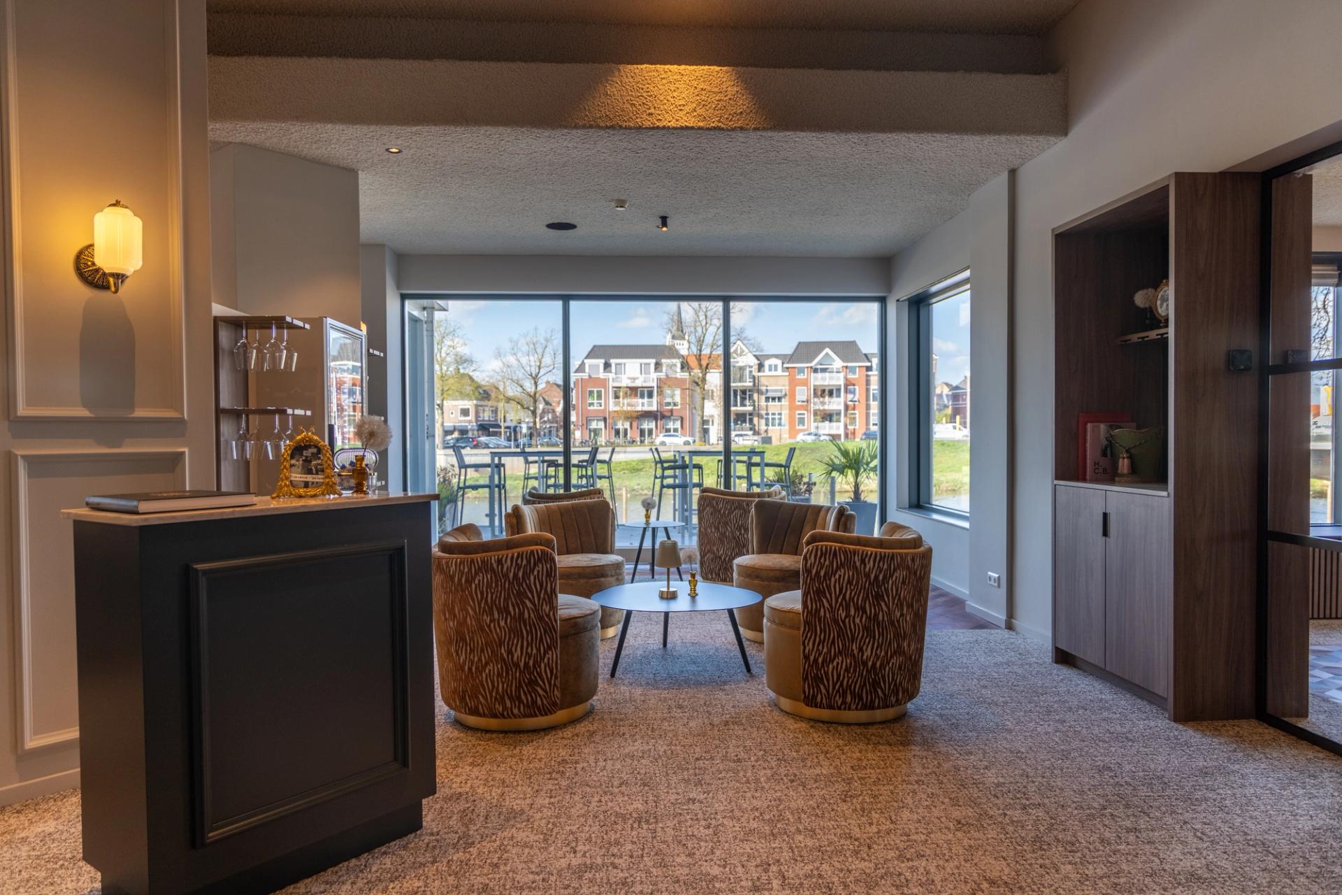 Elegant interieur van Brasserie Bresson bij Hotel de Zon in Ommen met gouden tafellampen, fluwelen stoelen en uitzicht op de Vecht