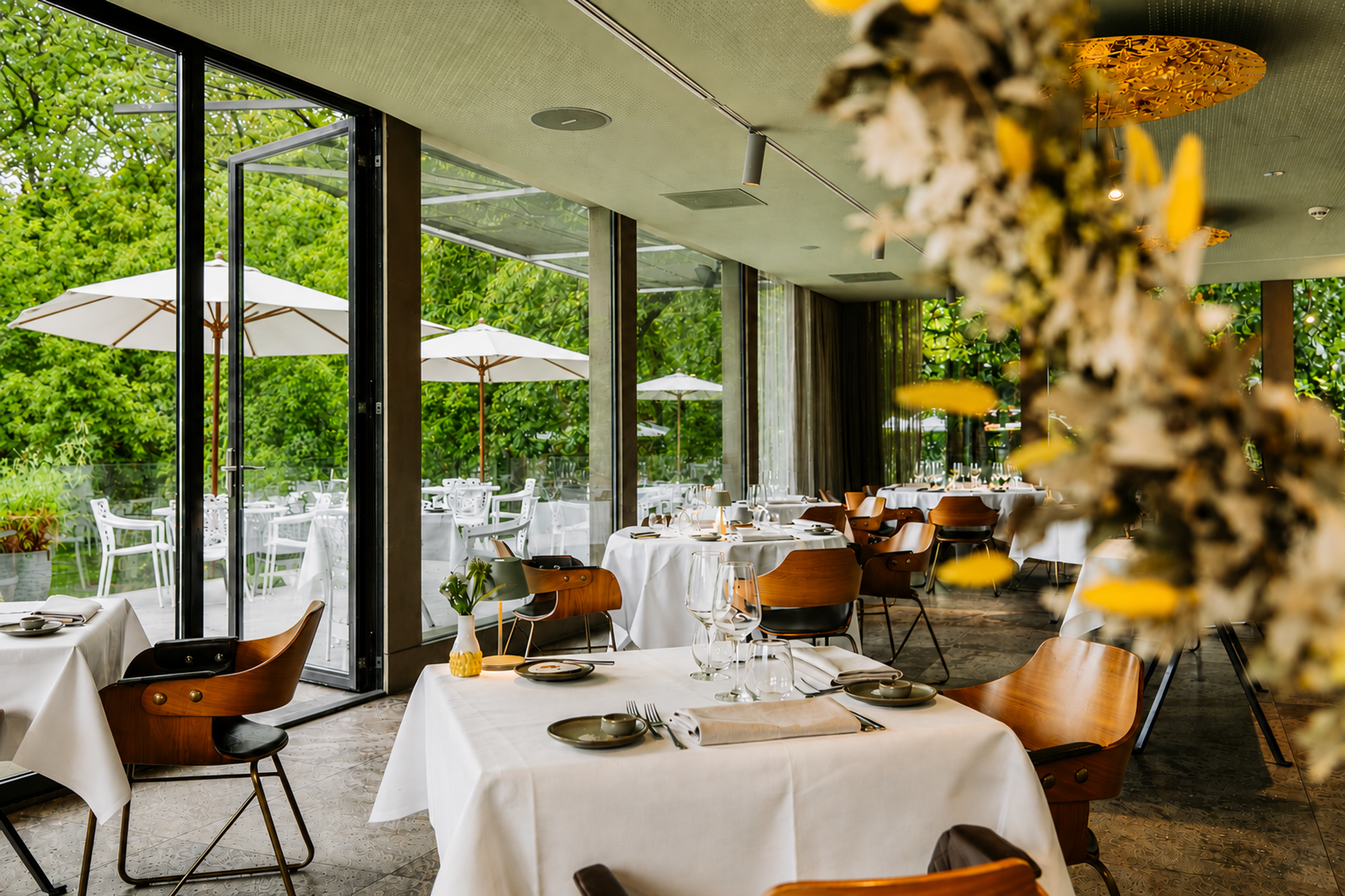 Lichte eetzaal van restaurant Pirandello in Winselerhof met witte tafels, houten stoelen en panoramisch uitzicht op de tuin