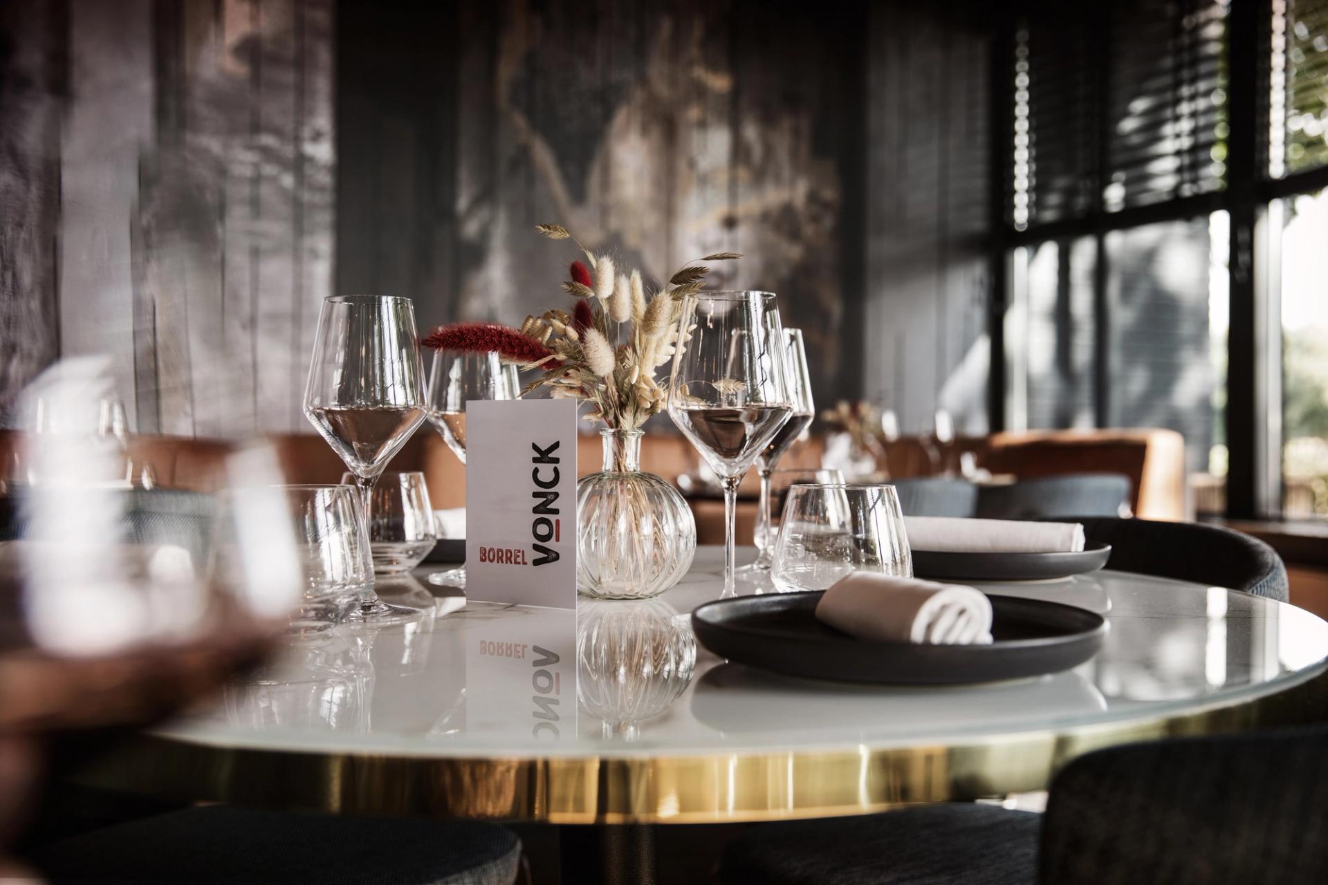 Interieur van Restaurant Vonck in Hotel Paping in Ommen met ronde tafels, blauwe stoelen, rieten hanglampen en groot kunstwerk