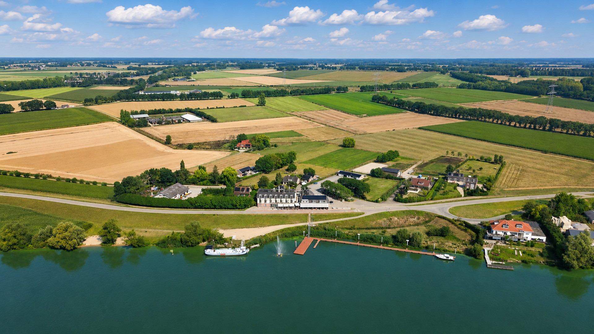 Luchtfoto van Hotel Hoogeerd in Niftrik aan recreatieplas De Gouden Ham, omringd door het rivierlandschap van het Land van Maas en Waal.