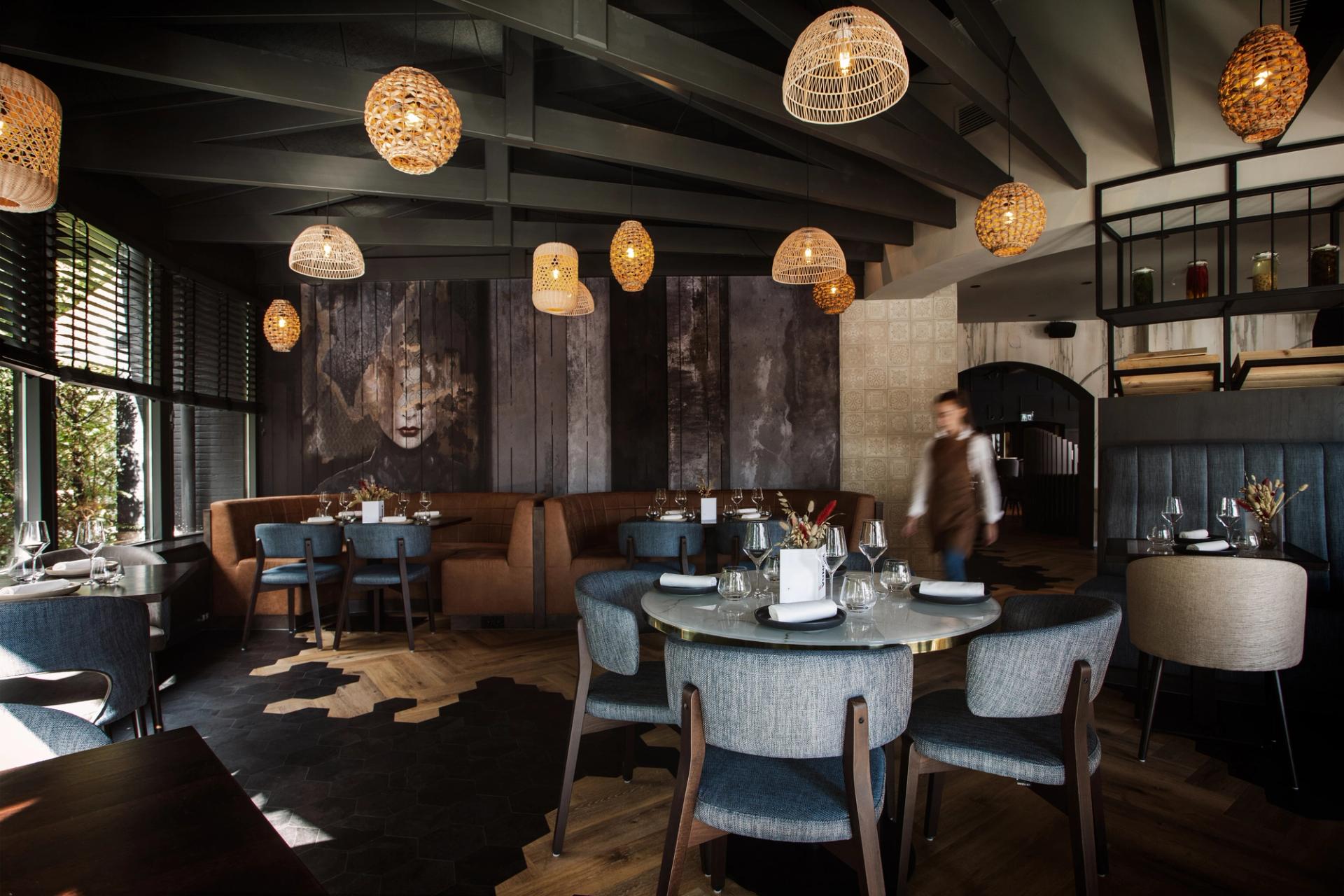 Sfeervol interieur van Restaurant Vonck bij Hotel Paping in Ommen met rotan hanglampen, ronde tafels en kunstwerk