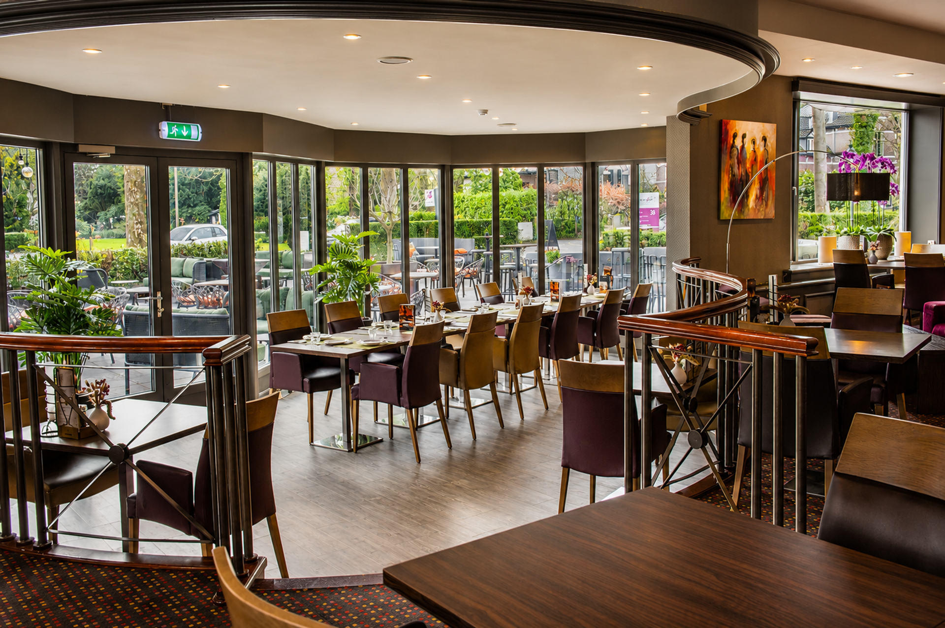 Licht restaurant van Hotel Hof van Gelre in Lochem met panoramische ramen, uitzicht op het terras en het groen