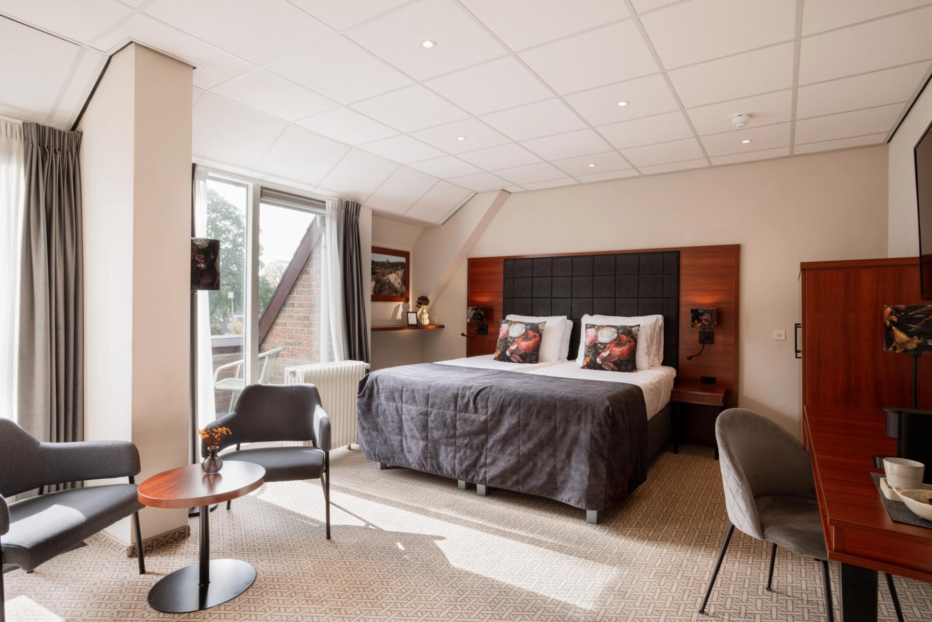 Suite met tweepersoonsbed, zithoek en balkon bij Hotel de Oringer Marke in Odoorn, Drenthe