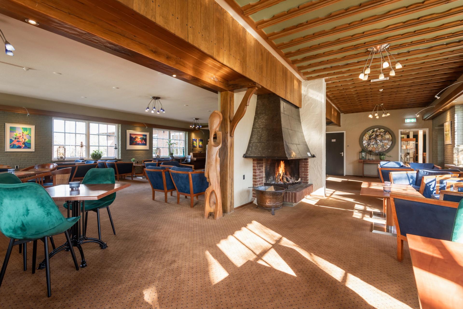 Stimmungsvolle Lounge mit brennendem Kamin, Holzbalken und Kunstwerken im Hotel de Landmarke in Ootmarsum, Twente