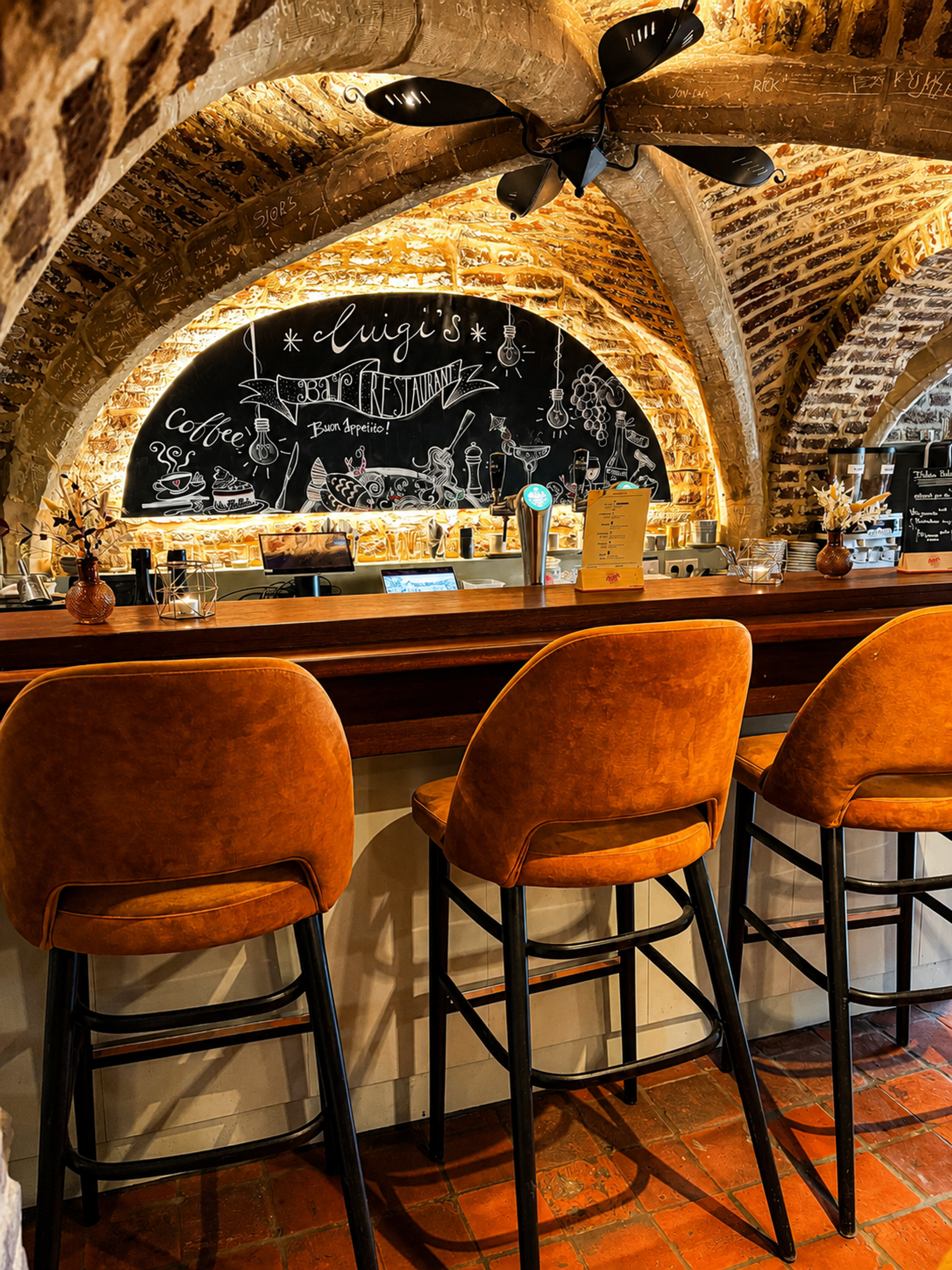 Bar van restaurant Luigi's in Winselerhof met oranje barkrukken, bakstenen gewelf en krijtbord met 'Buon Appetito'
