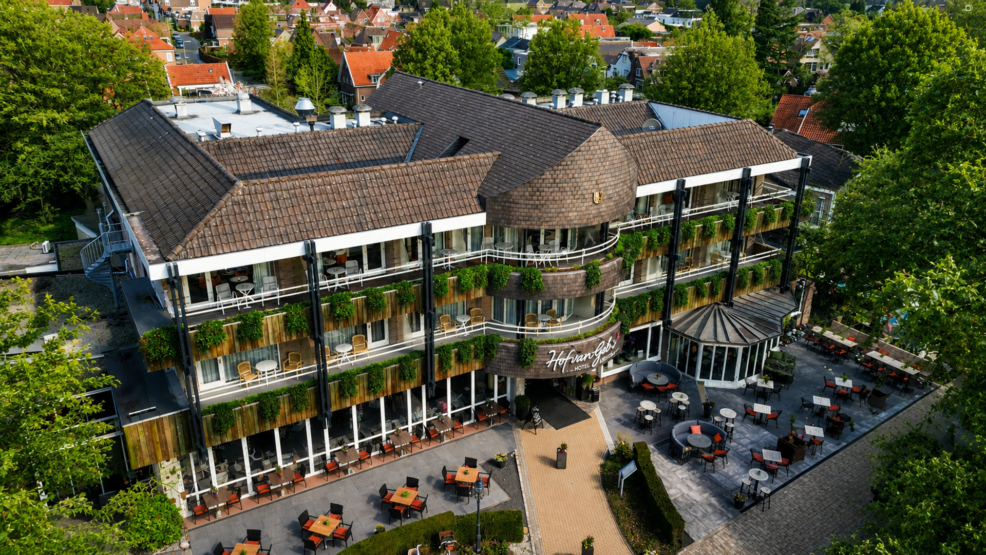 Luchtfoto van Hotel Hof van Gelre in Lochem met begroeide gevels, balkons en terras verscholen in het groen