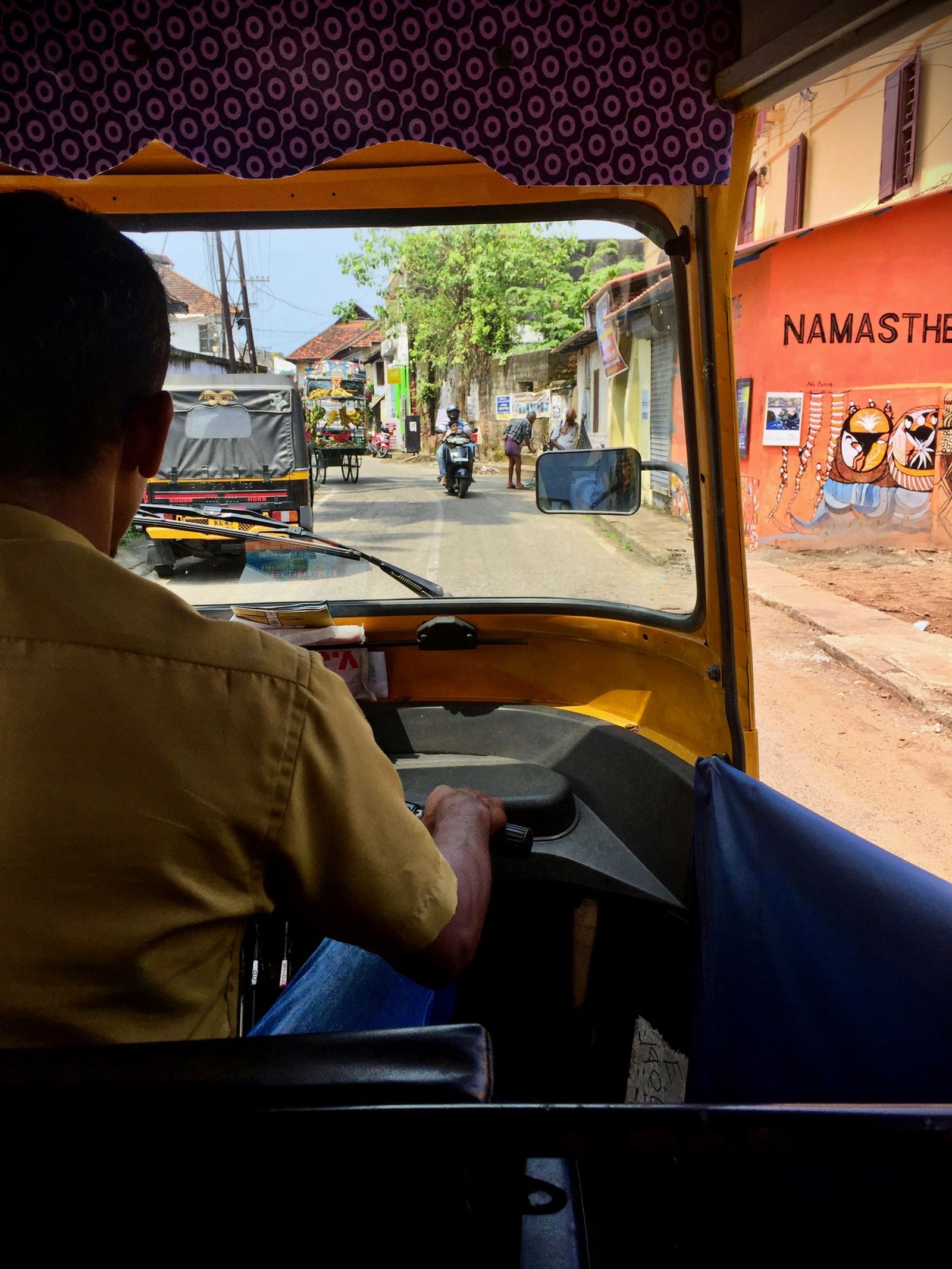 The view over a tuk-tuk driver’s shoulder onto a Fort Kochi street