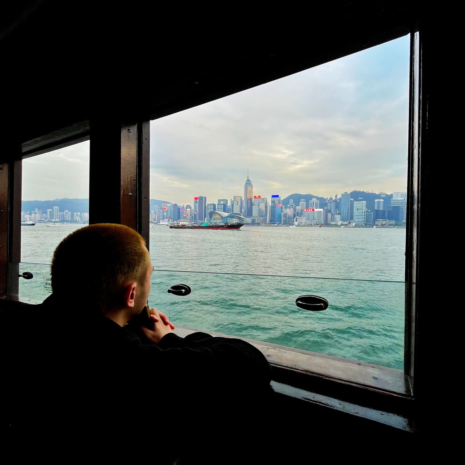 A passenger watching Hong Kong harbour from a ferry window