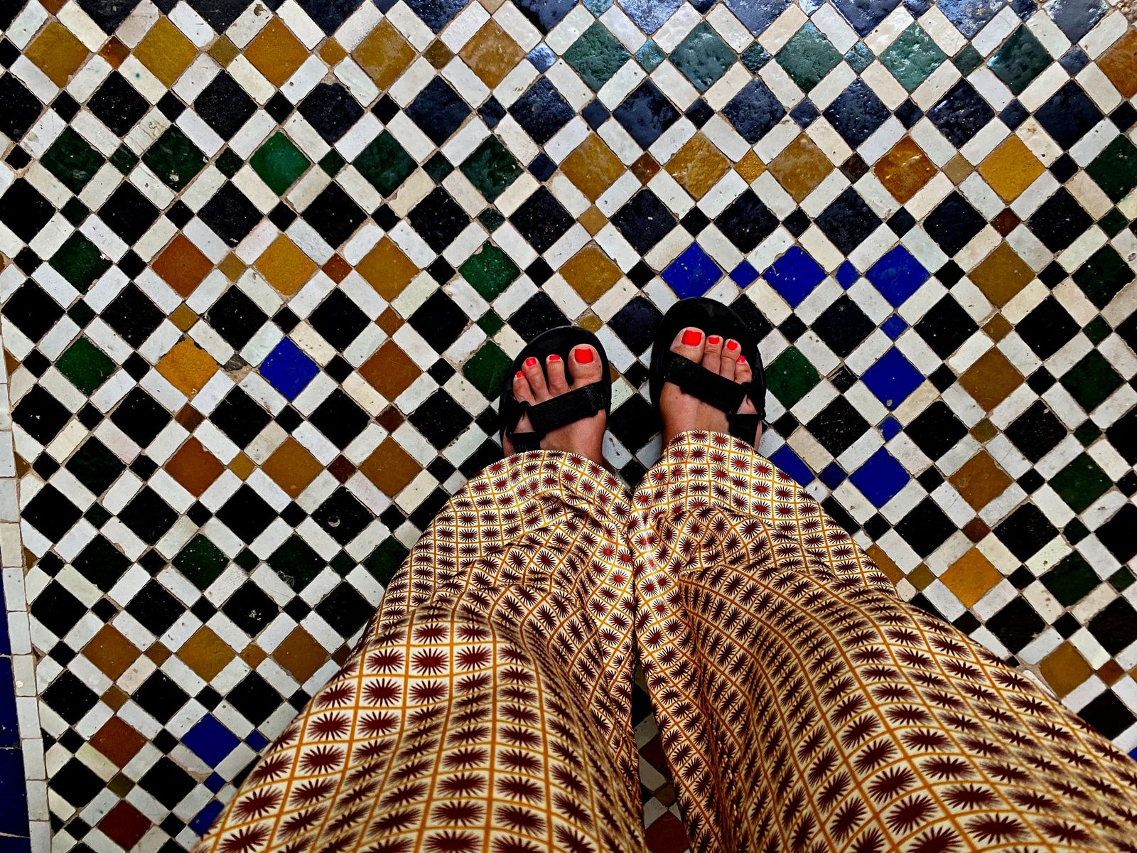 Bare feet in sandals on a zellige tiled floor