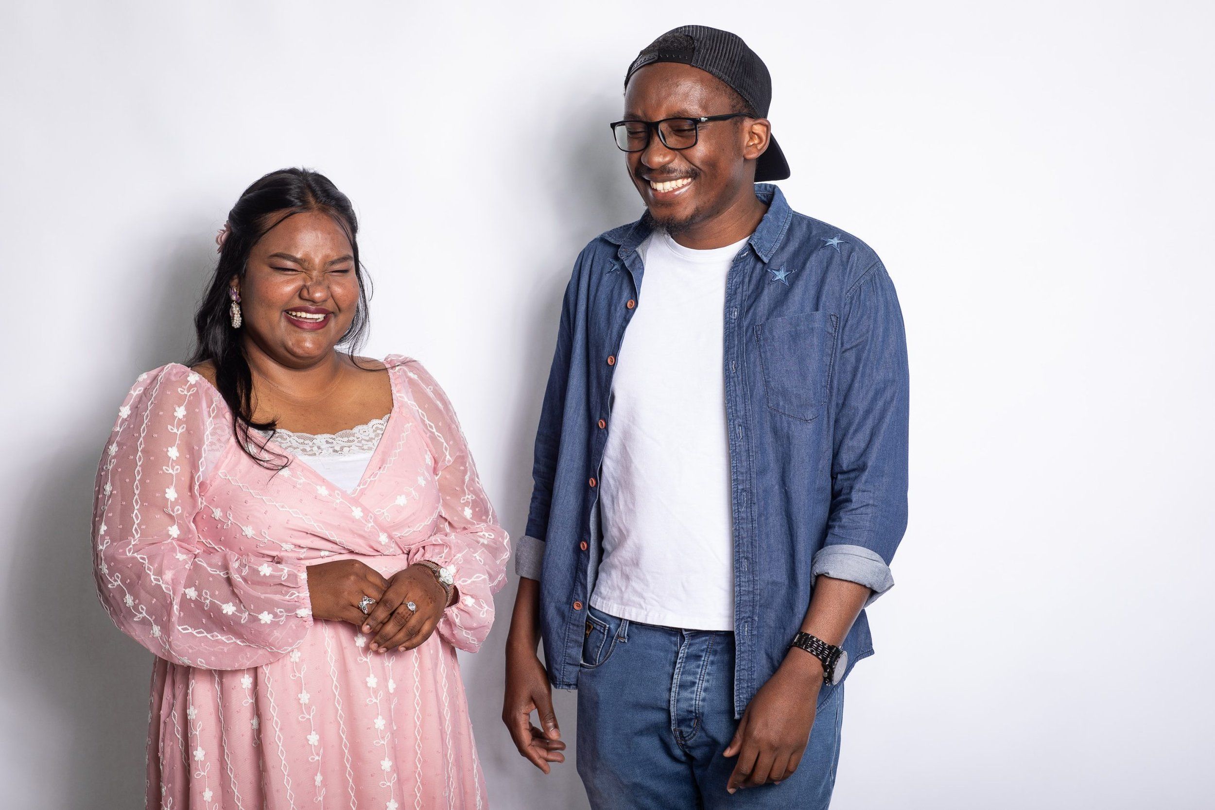 Two San Francisco Bay University students laughing together against a plain white studio backdrop