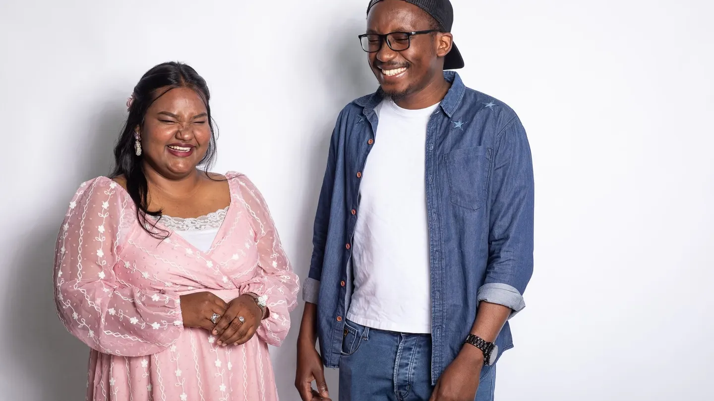 Two San Francisco Bay University students laughing together against a plain white studio backdrop