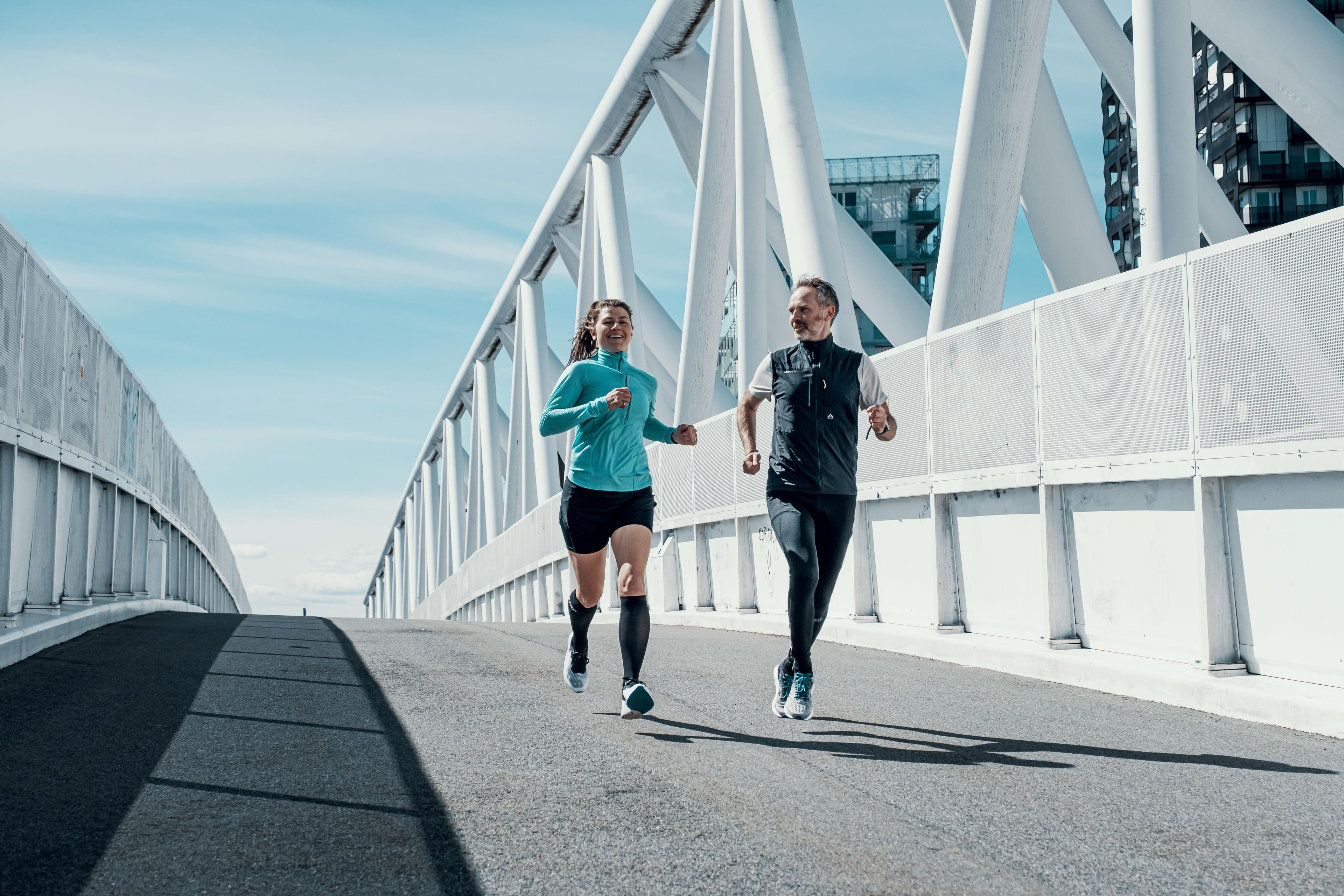 Mann og dame løper utendørs over bro