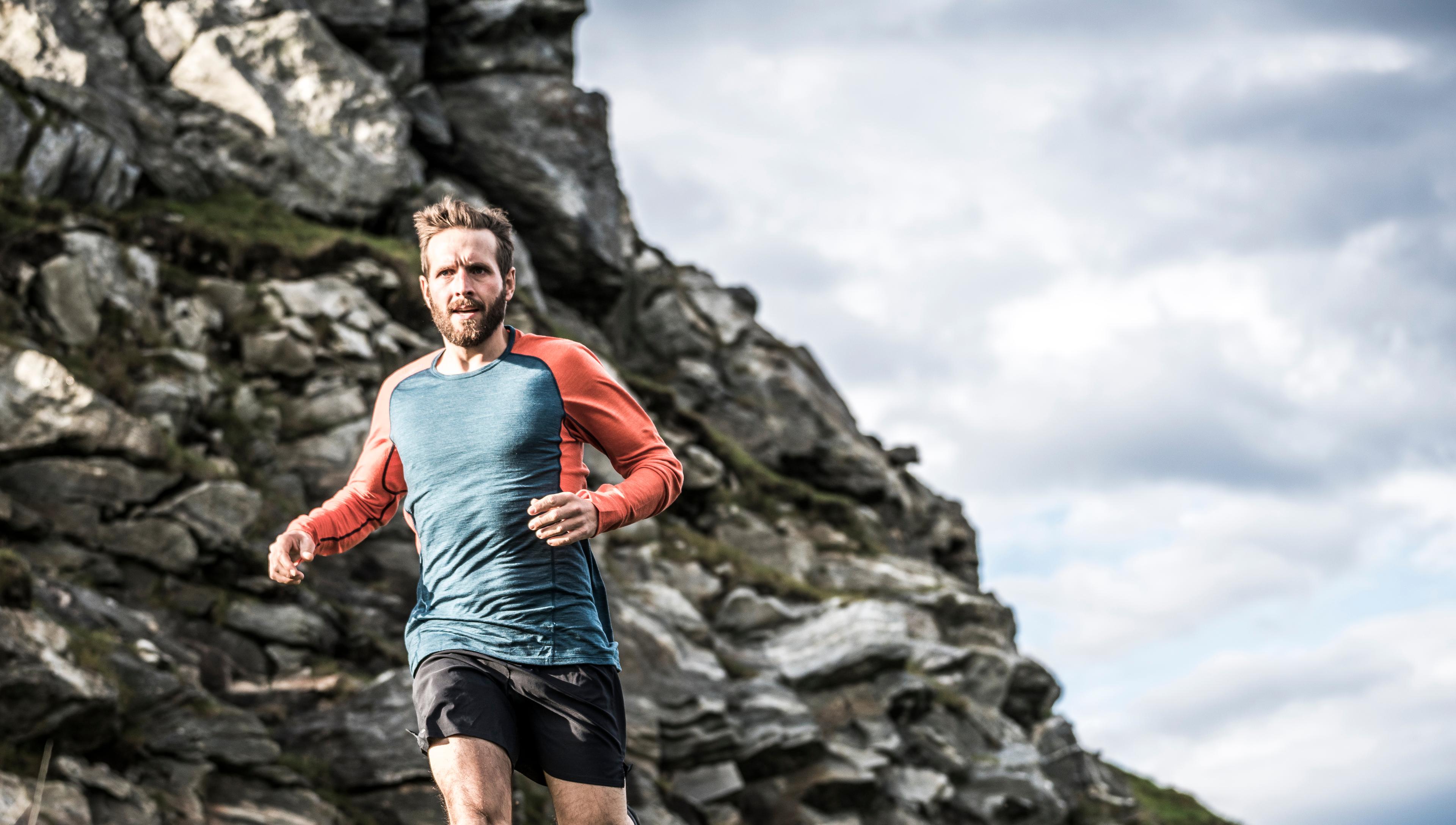 Mann i Devold treningsklær løper i fjellet