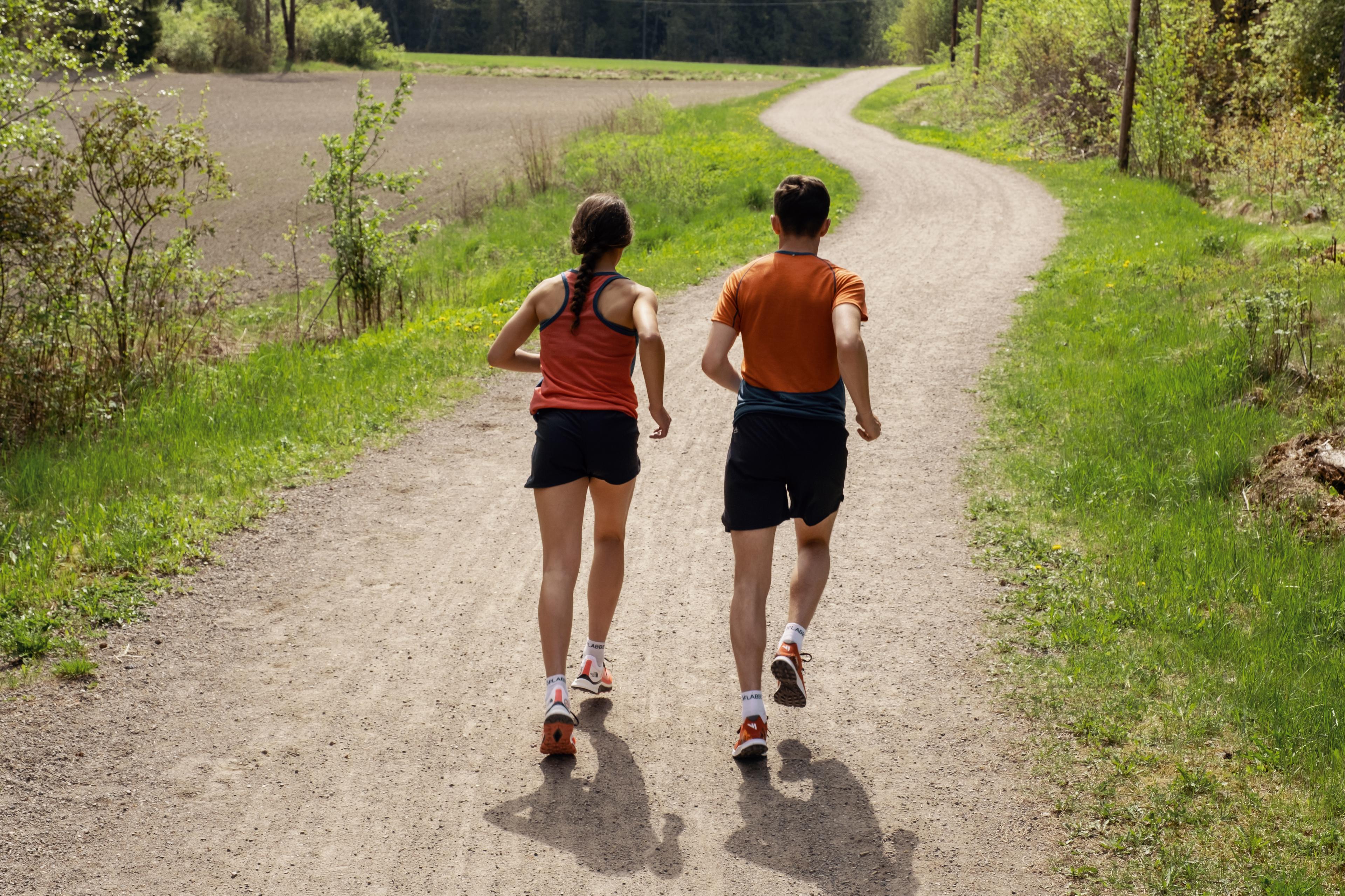 Mann og dame løper utendørs på grussti