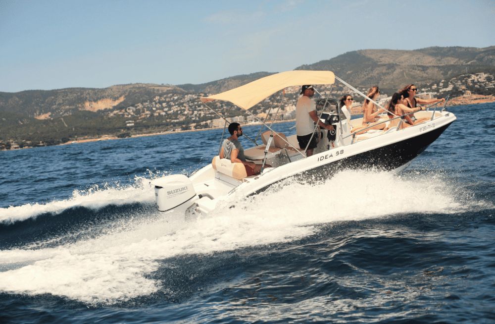 Barco privado fondeado en una cala de aguas turquesas en Mallorca con patrón a bordo