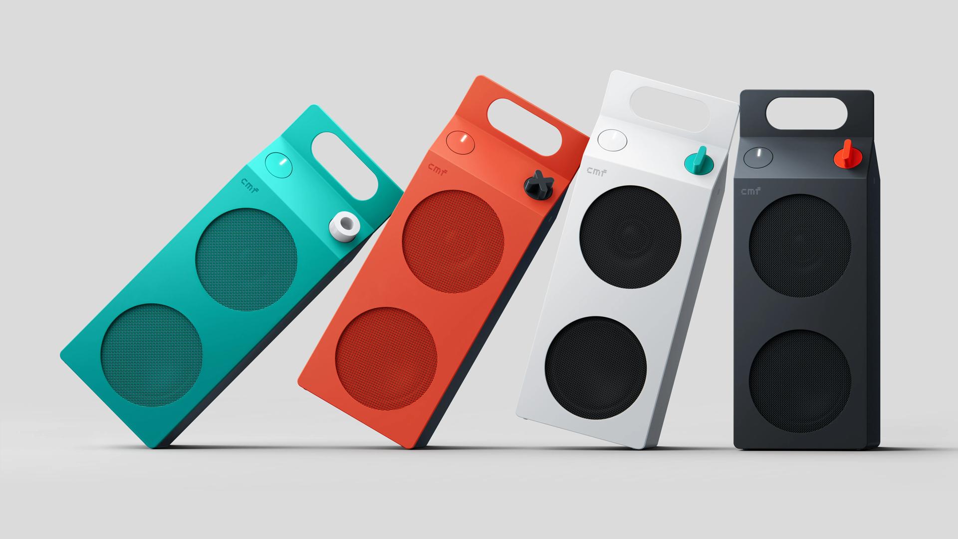 Quatre enceintes CMF Speaker M turquoise, orange, blanche et gris foncé, avec poignée intégrée et molette de contrôle.