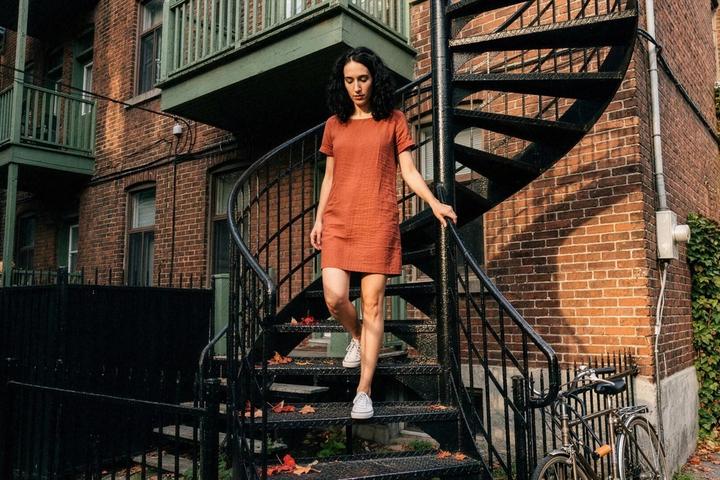 A woman in a sleeveless dress walks down an outdoor spiral staircase on a Plateau street in Montreal.