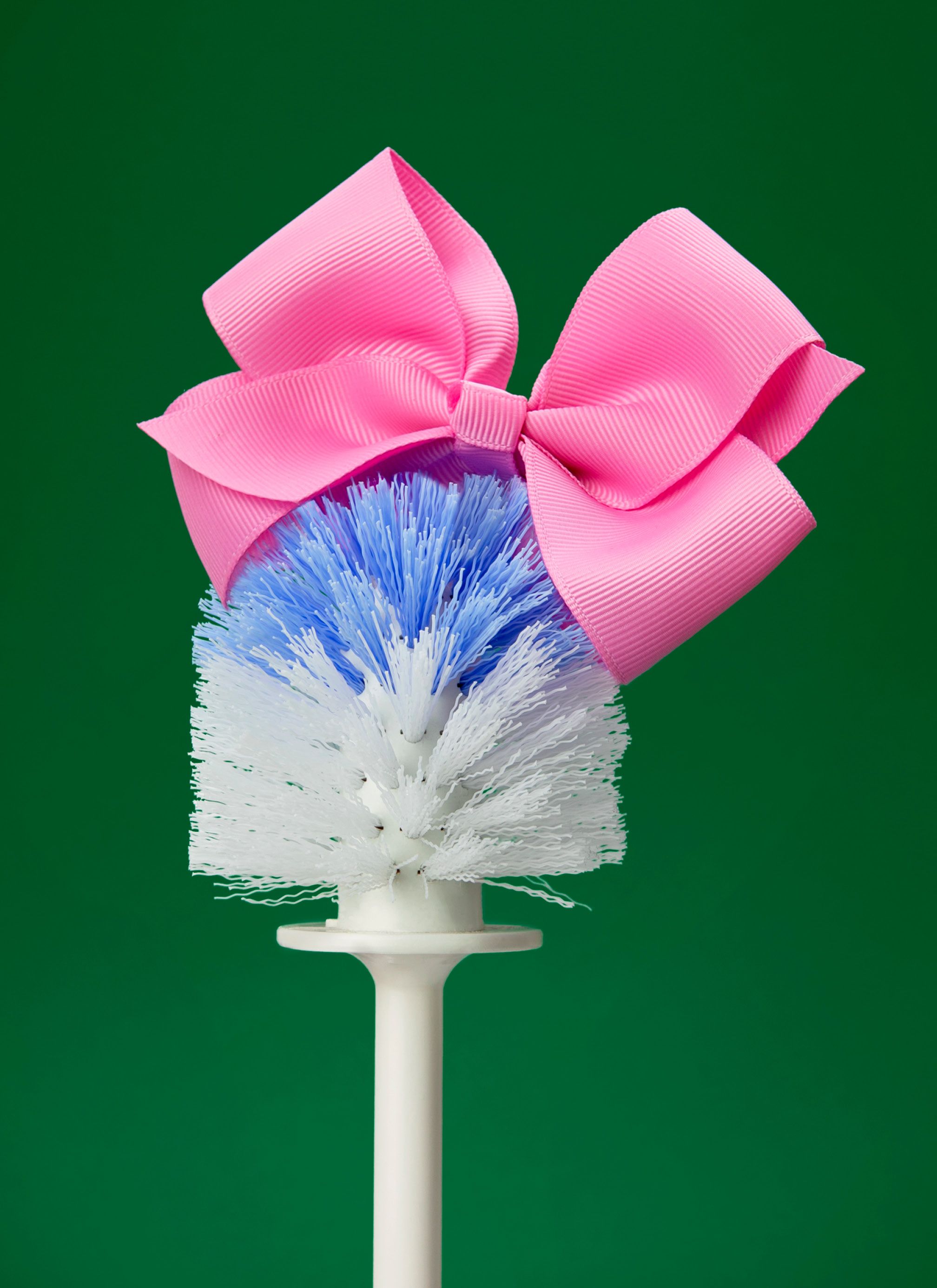 A toilet brush wearing a pink bow.