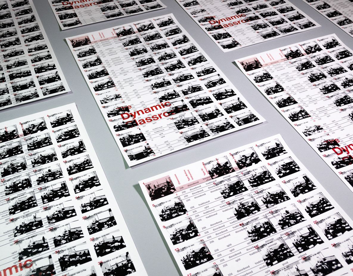 Grid of posters laid on a gray surface. The posters are minimalist Swiss designs with a grid of black and white photos of classrooms and a data table, overlaid with red text that reads “The Dynamic Classroom.”