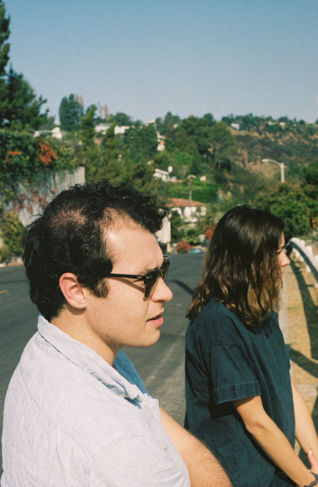 Two people stand on the side of a road in the Los Angeles hills