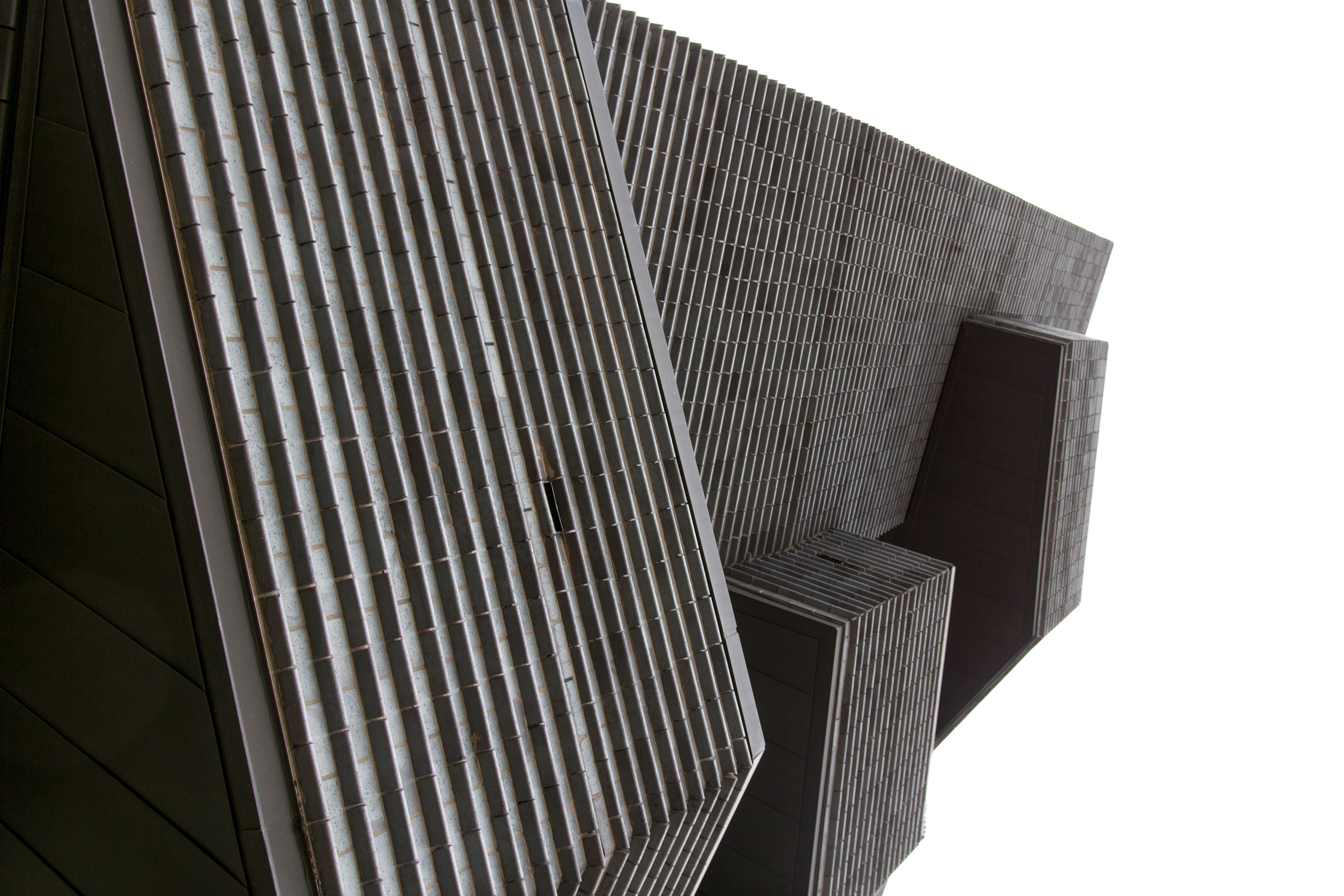 A modern black brick building, photographed at an angle that makes it unclear which way is up.