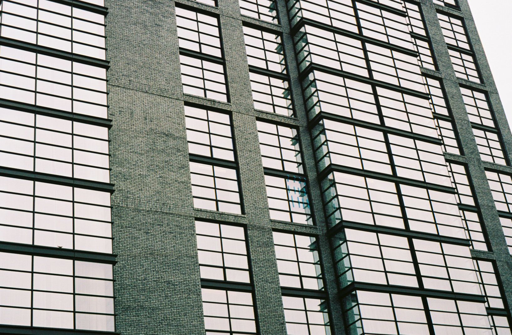 A 35mm film photograph of AC Hotel in Washington, DC. Its architecture is simple: black brick and glass.