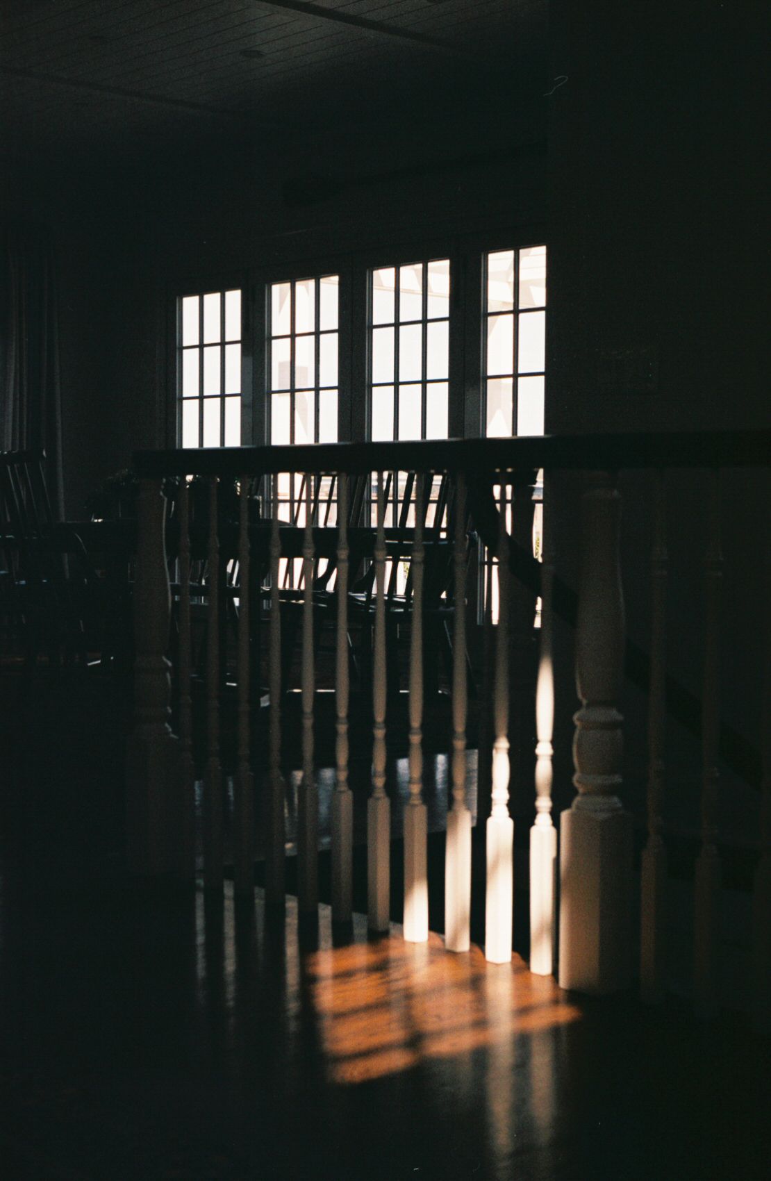 35mm film photograph of light shining through window onto wooden floor and staircase handrail.