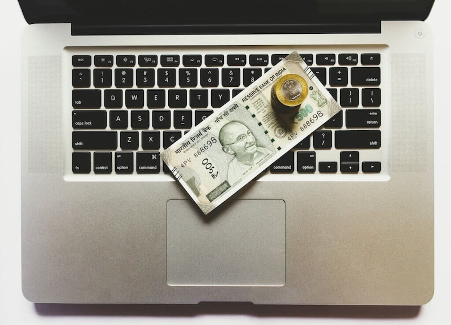 A laptop with cash on the keyboard, symbolizing bootstrap funding and self financing startup growth.