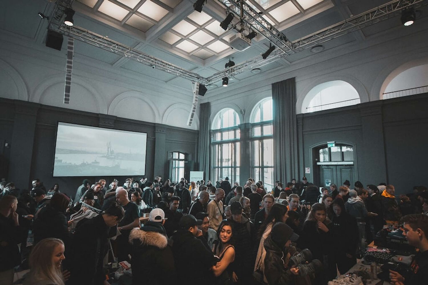 A vibrant network event with people, and a speaker on stage.
