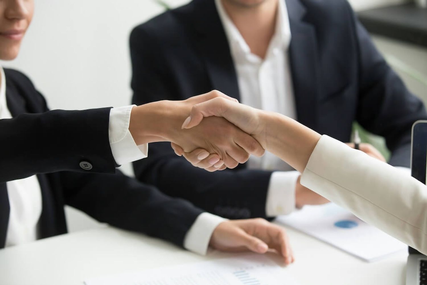 Two people shaking hands, symbolizing the decision between founder-led sales and hiring a sales team.