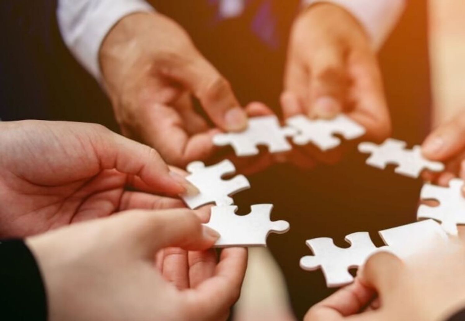 Image of diverse team members holding puzzle pieces together, symbolizing strong remote team culture.