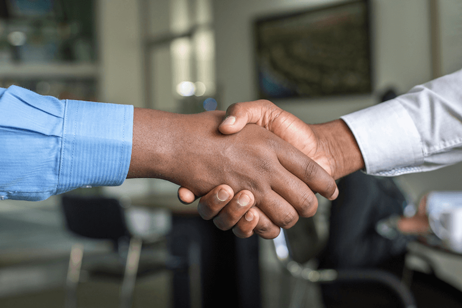 Two people shaking hands, symbolizing what is shareholders agreement (SHA) and collaboration in a business context.