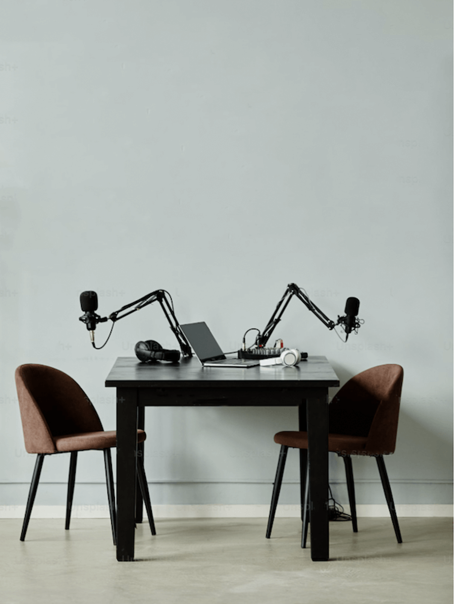 Podcast setup with two chairs and microphones, ready for recording in a minimalist studio setting.