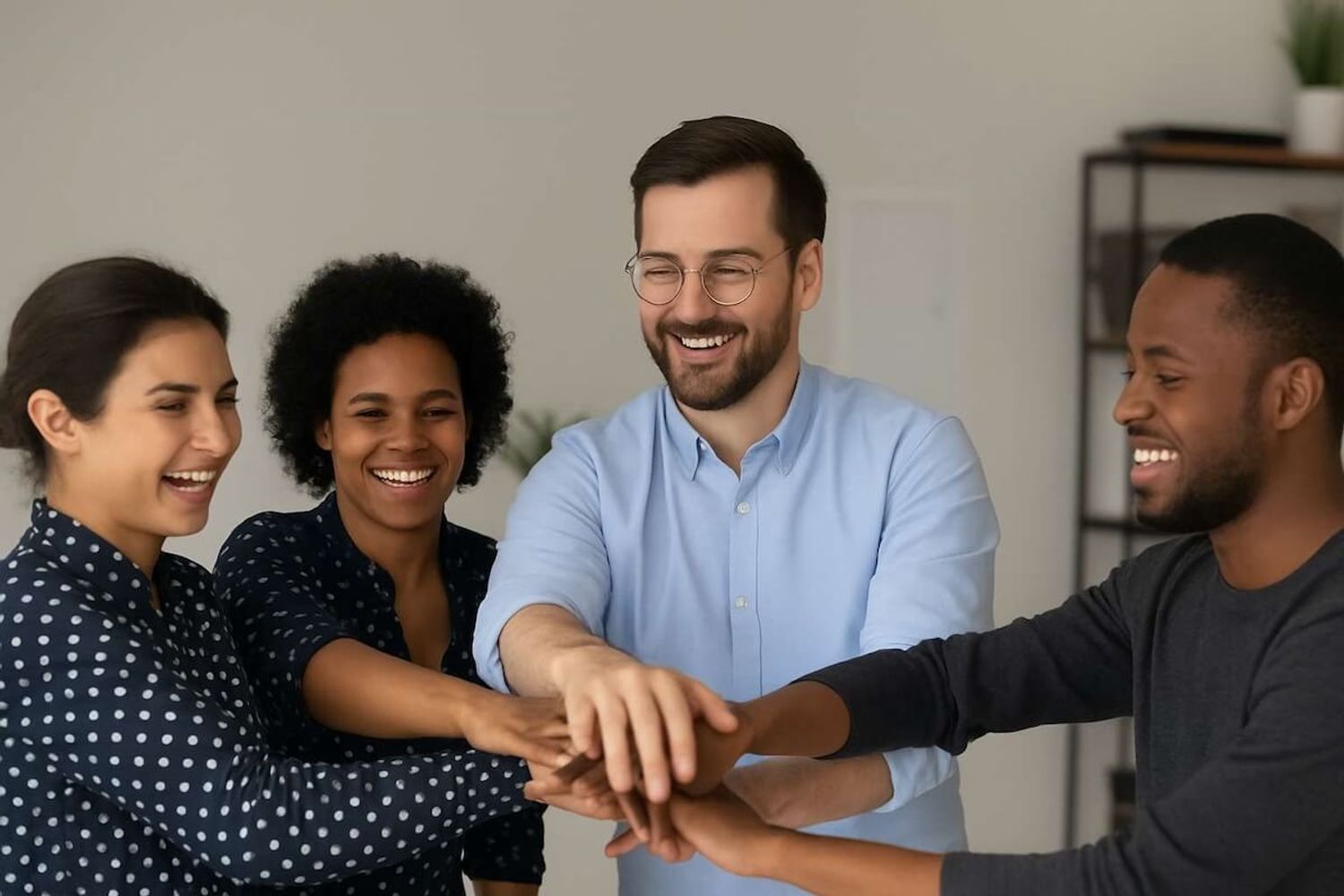 Startup team smiling with hands stacked, showing unity and team-building spirit.