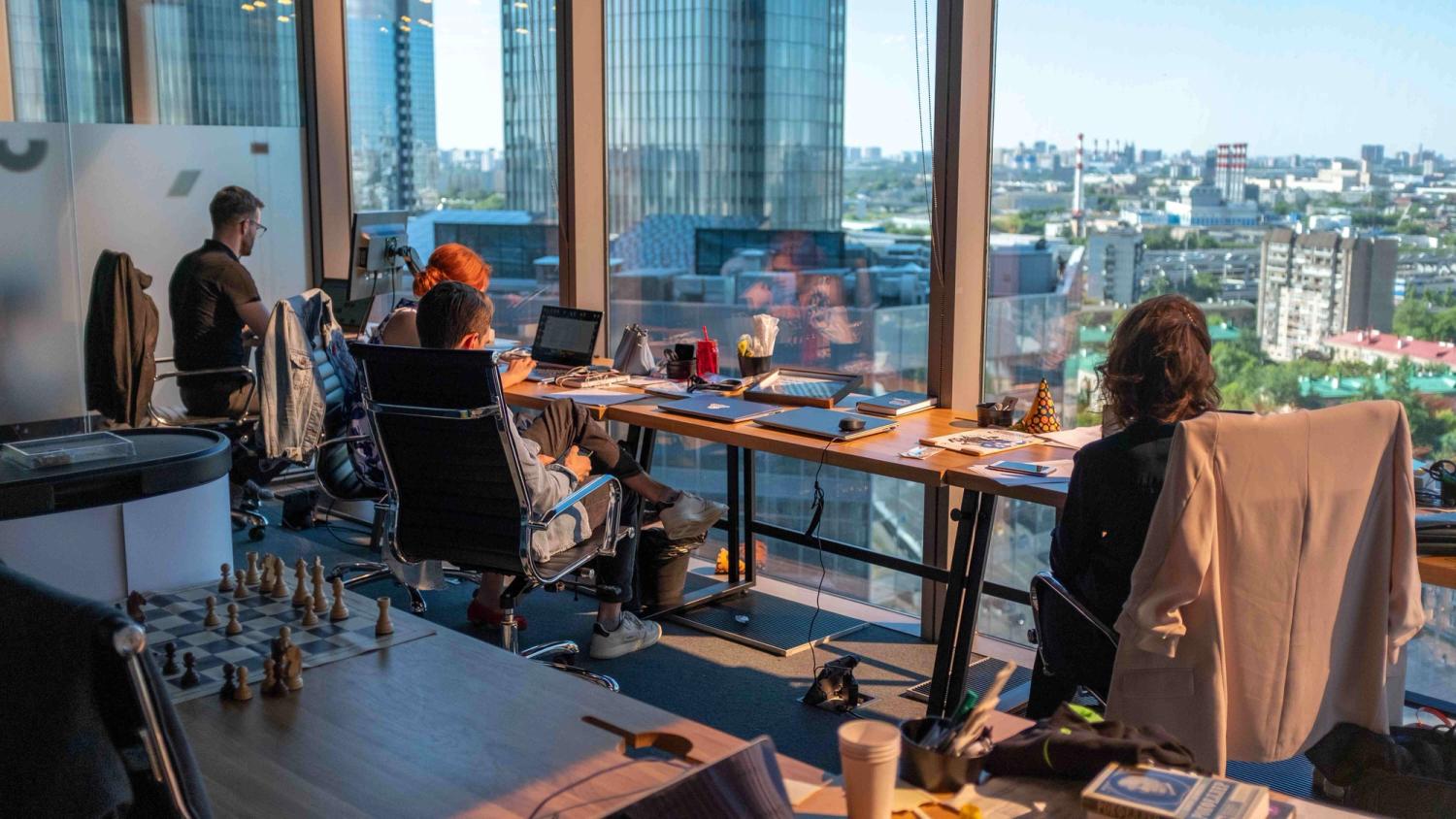 a four people team working on their office spaces while having a city view in the background